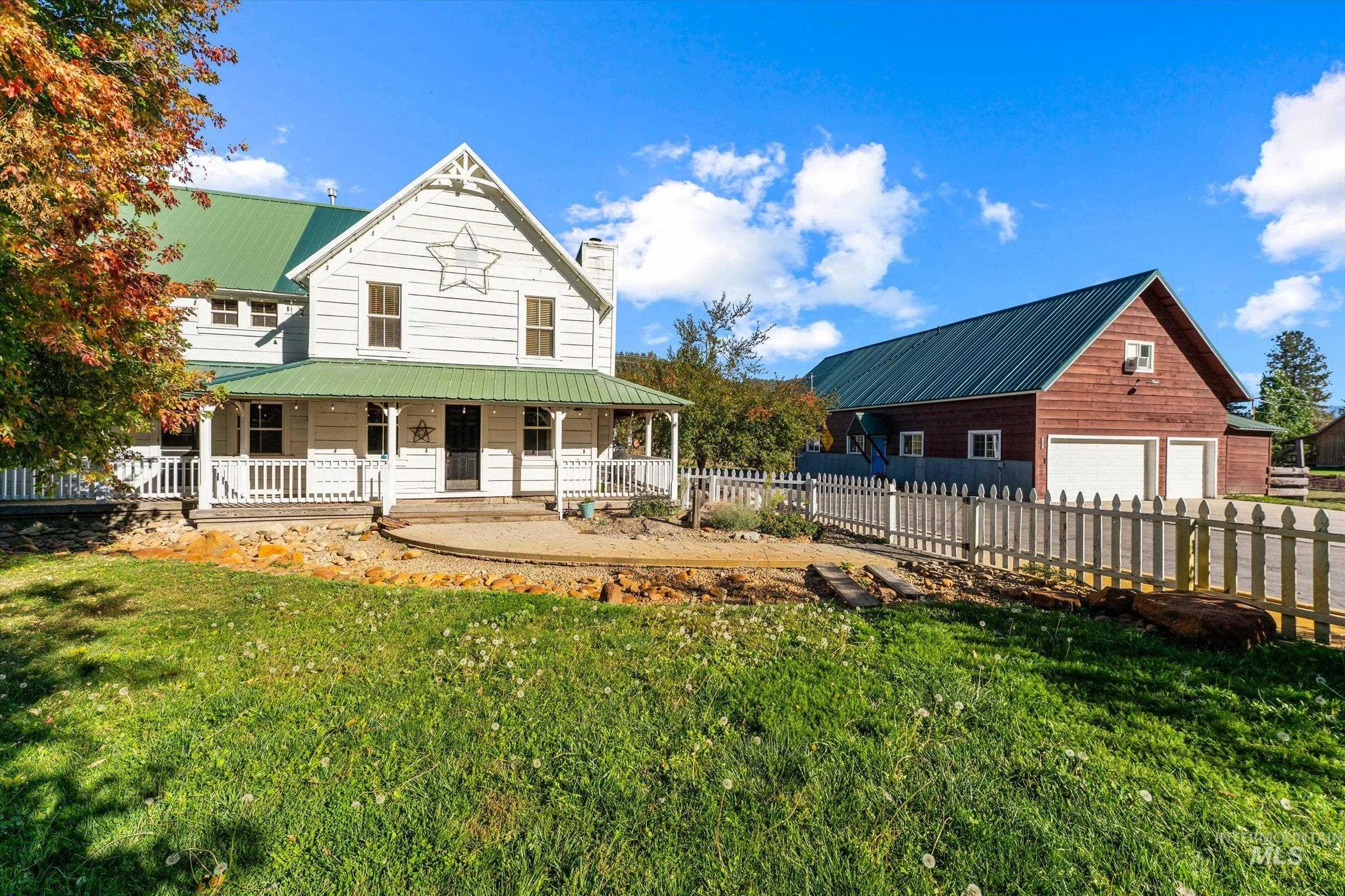 Back of property featuring covered porch, a chimney, a metal roof, and an outbuilding
