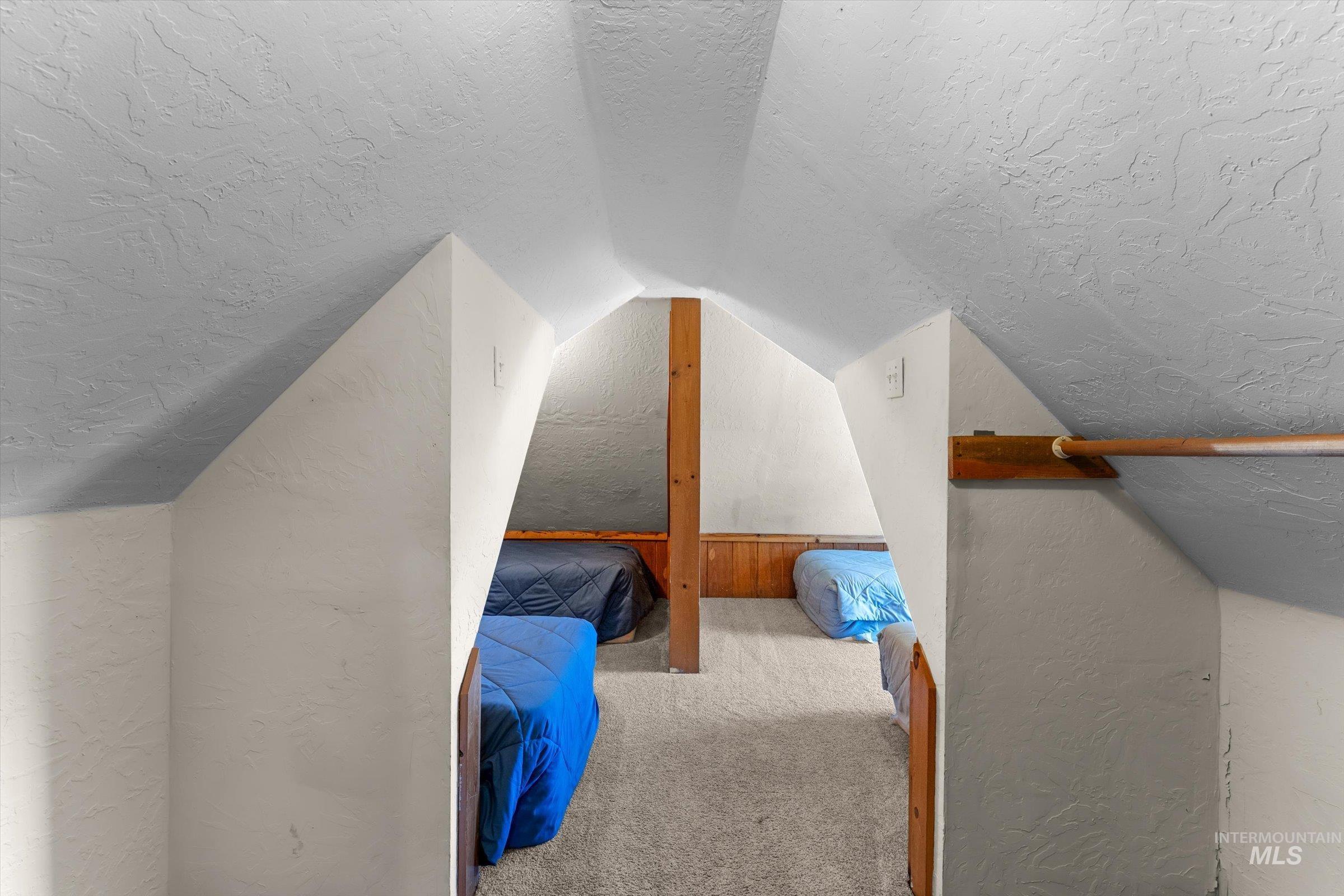 Bonus room with a textured ceiling, carpet, lofted ceiling, and a textured wall