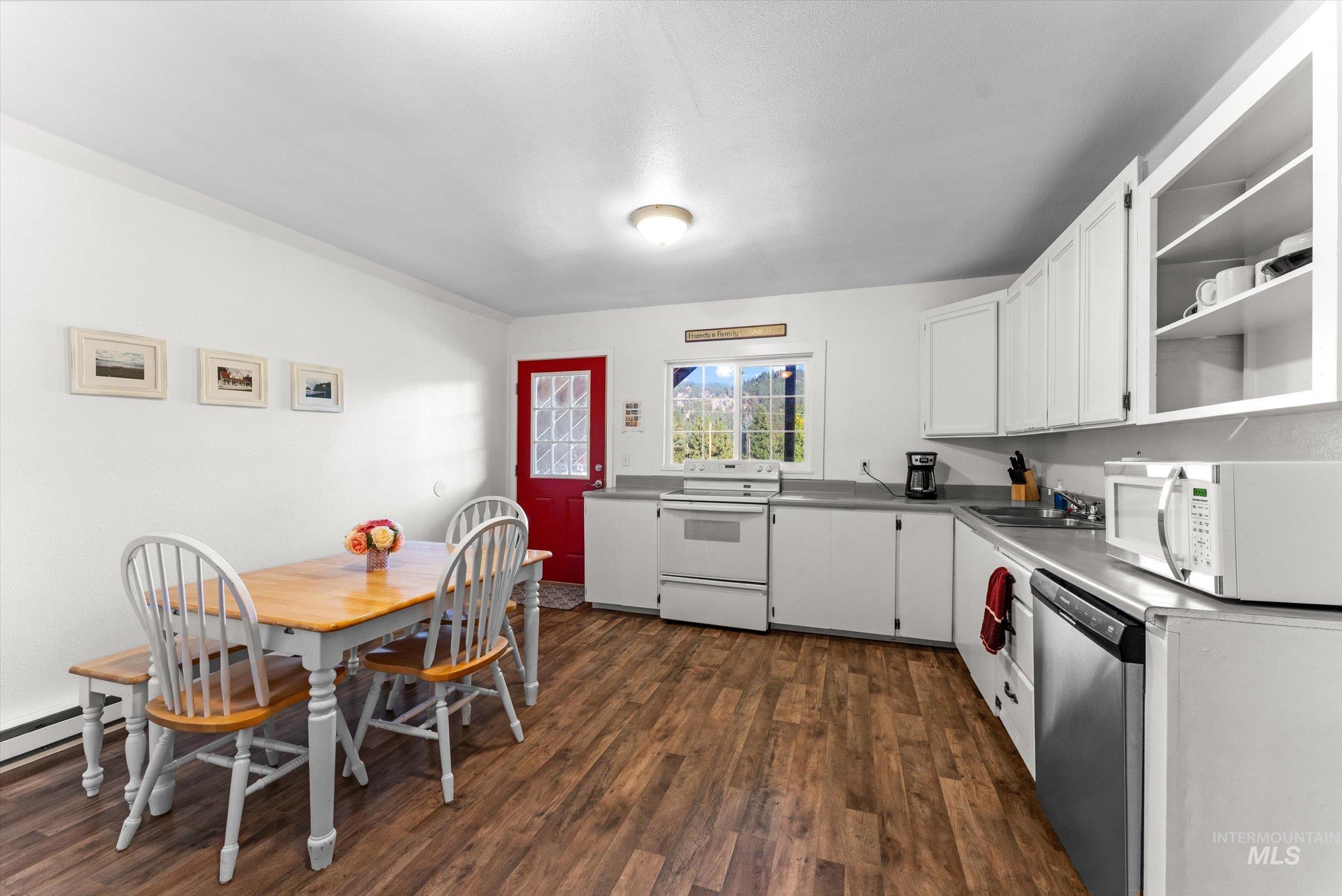 Kitchen with open shelves, white appliances, dark wood-style floors, and white cabinetry