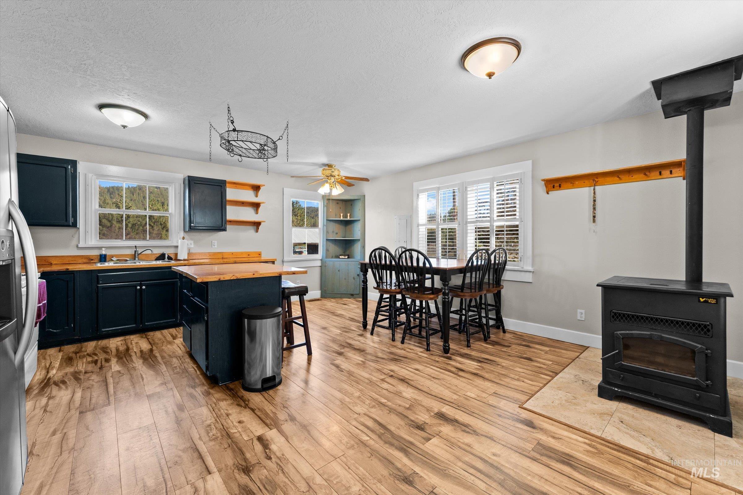Kitchen with a wood stove, open shelves, dark cabinetry, a breakfast bar area, and butcher block countertops