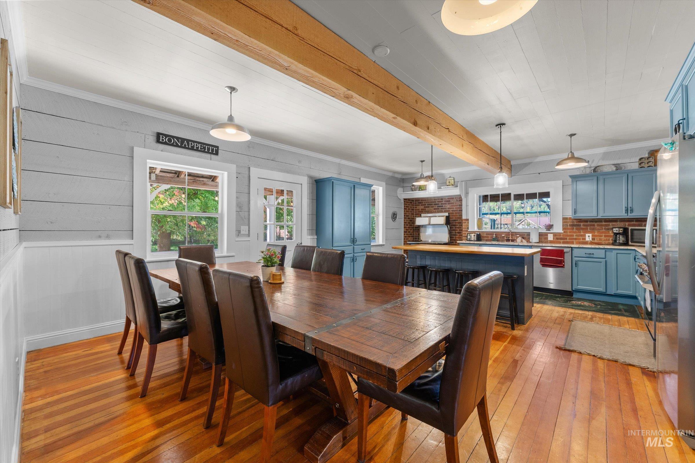 Dining room featuring light wood finished floors, ornamental molding, and beam ceiling