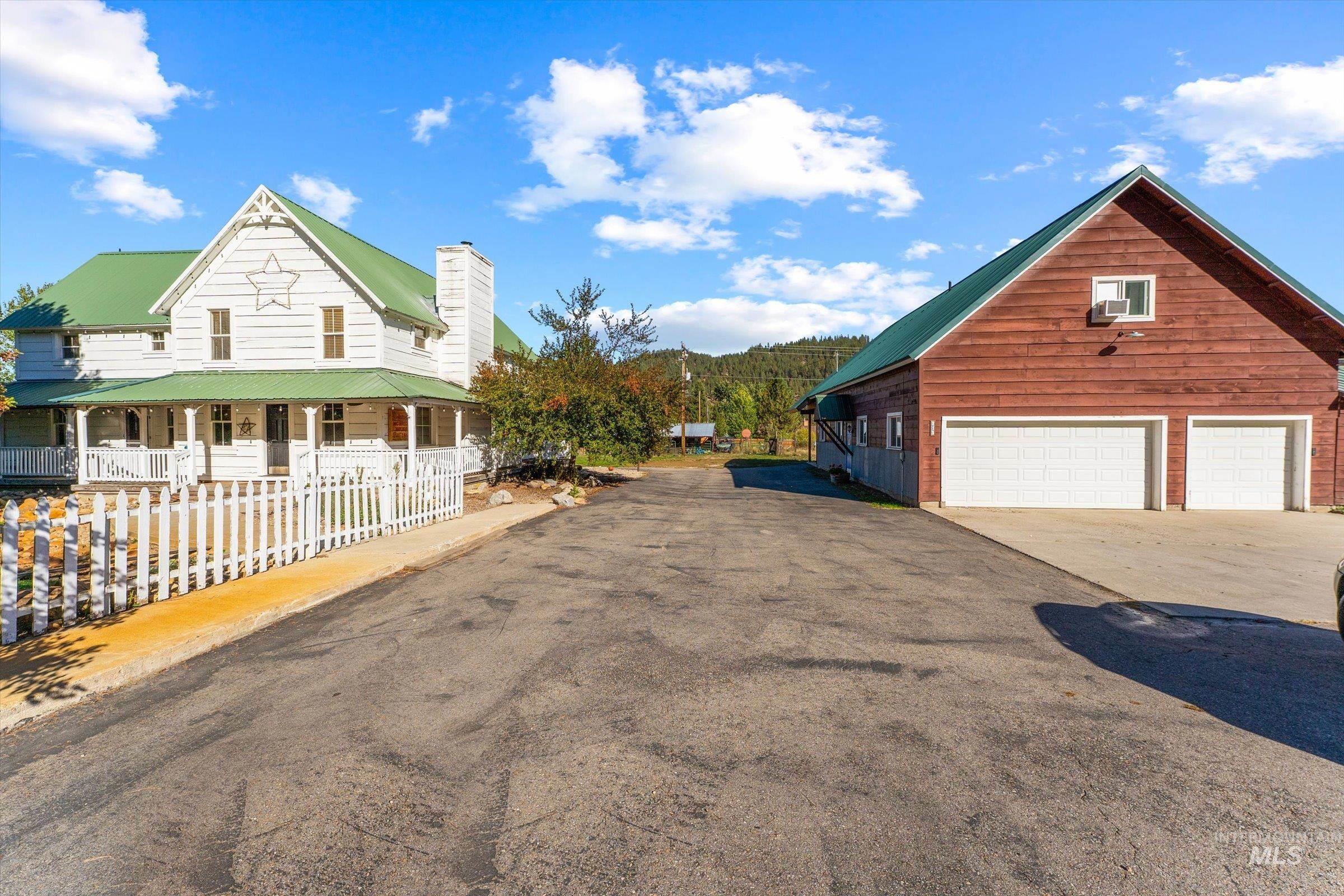 View of side of property with a metal roof, a porch, asphalt driveway, and a garage