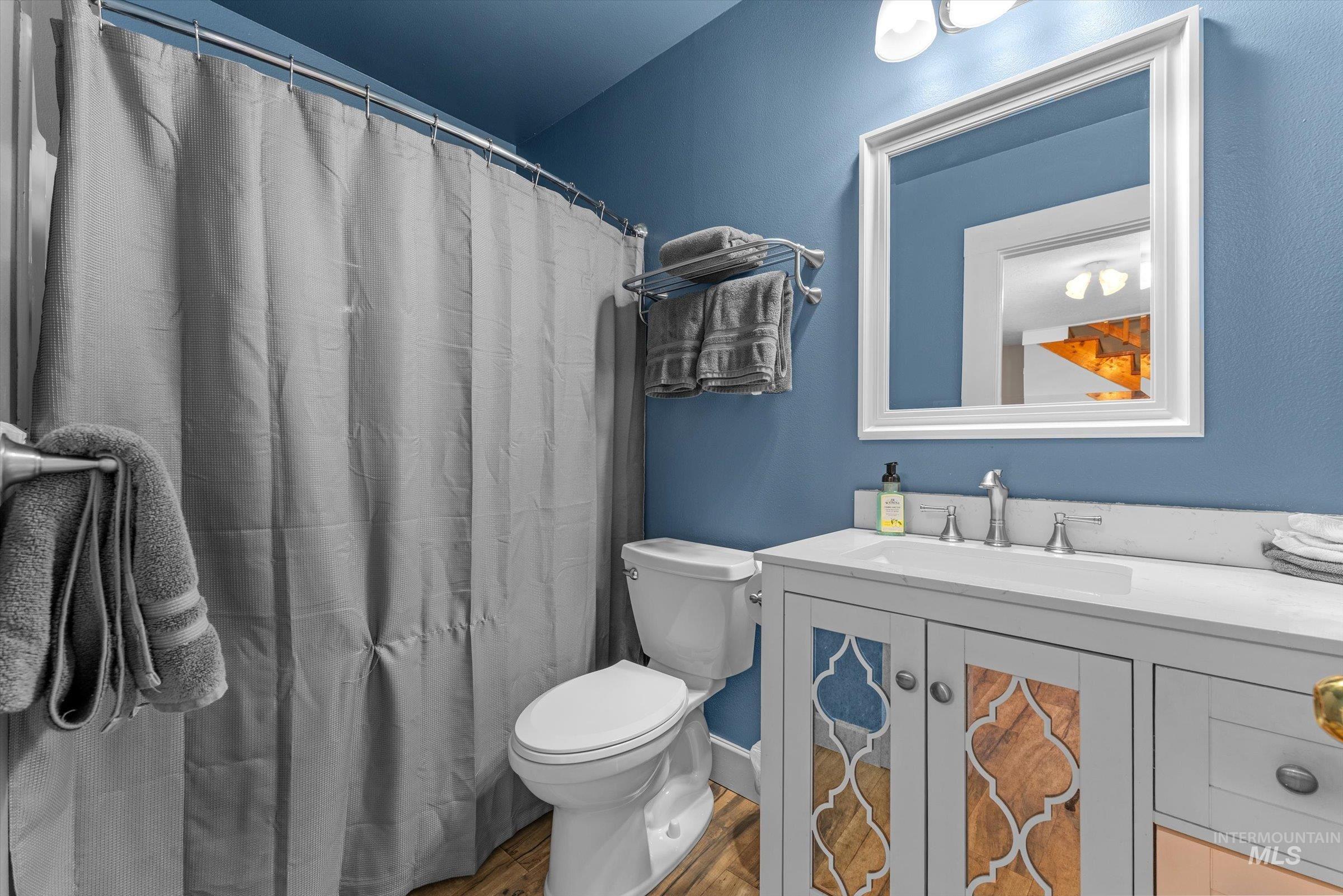 Full bath featuring vanity, wood finished floors, and a shower with curtain