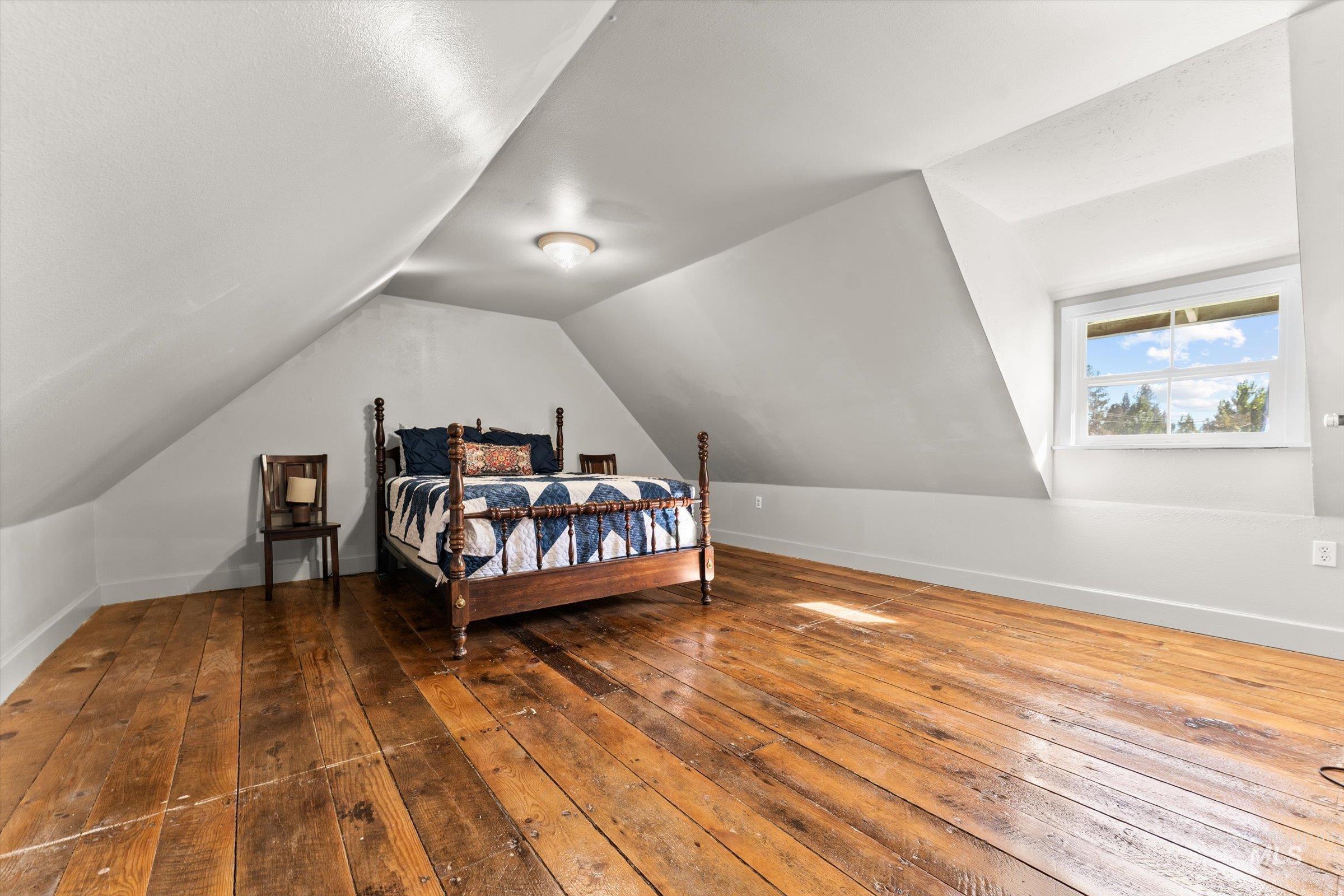 Bedroom with hardwood / wood-style floors and vaulted ceiling