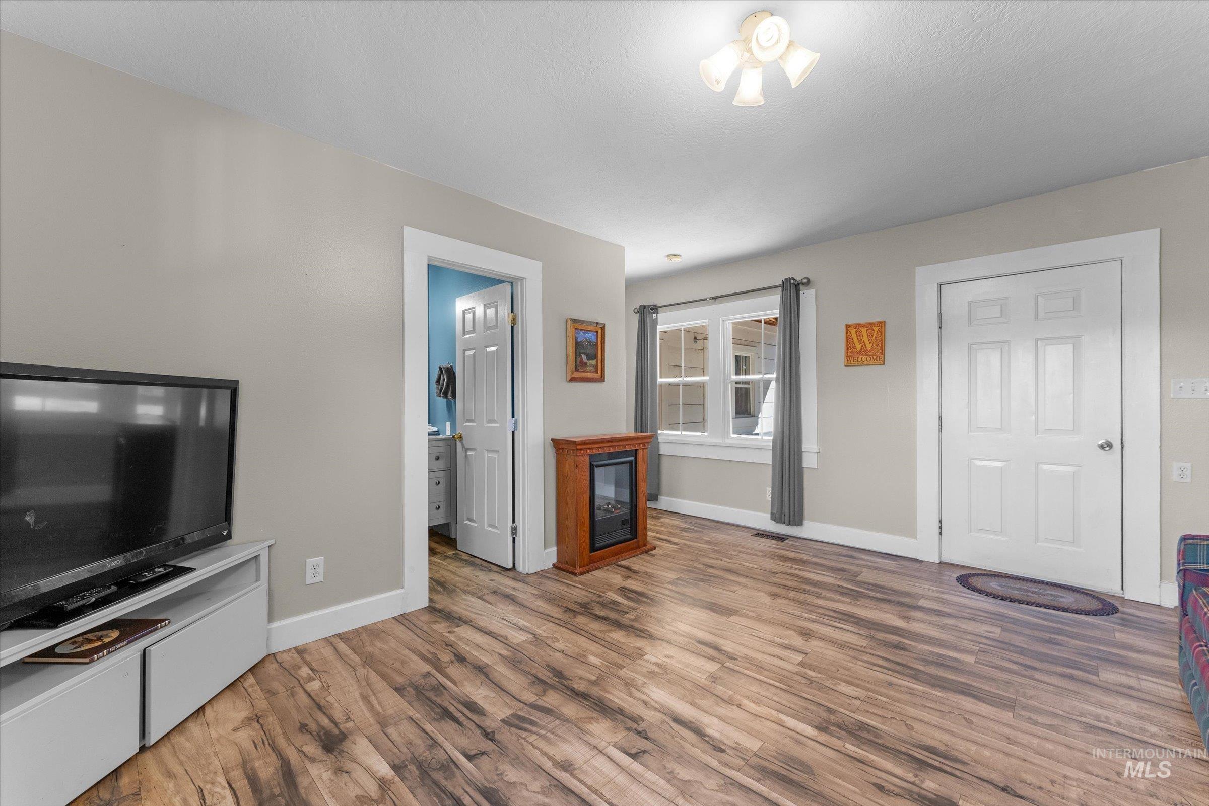 Unfurnished living room featuring wood finished floors and a glass covered fireplace