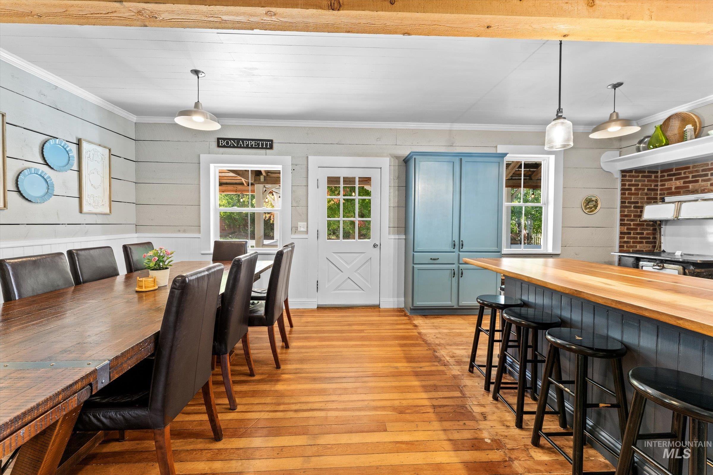Dining area featuring light wood-style floors, ornamental molding, and wood walls