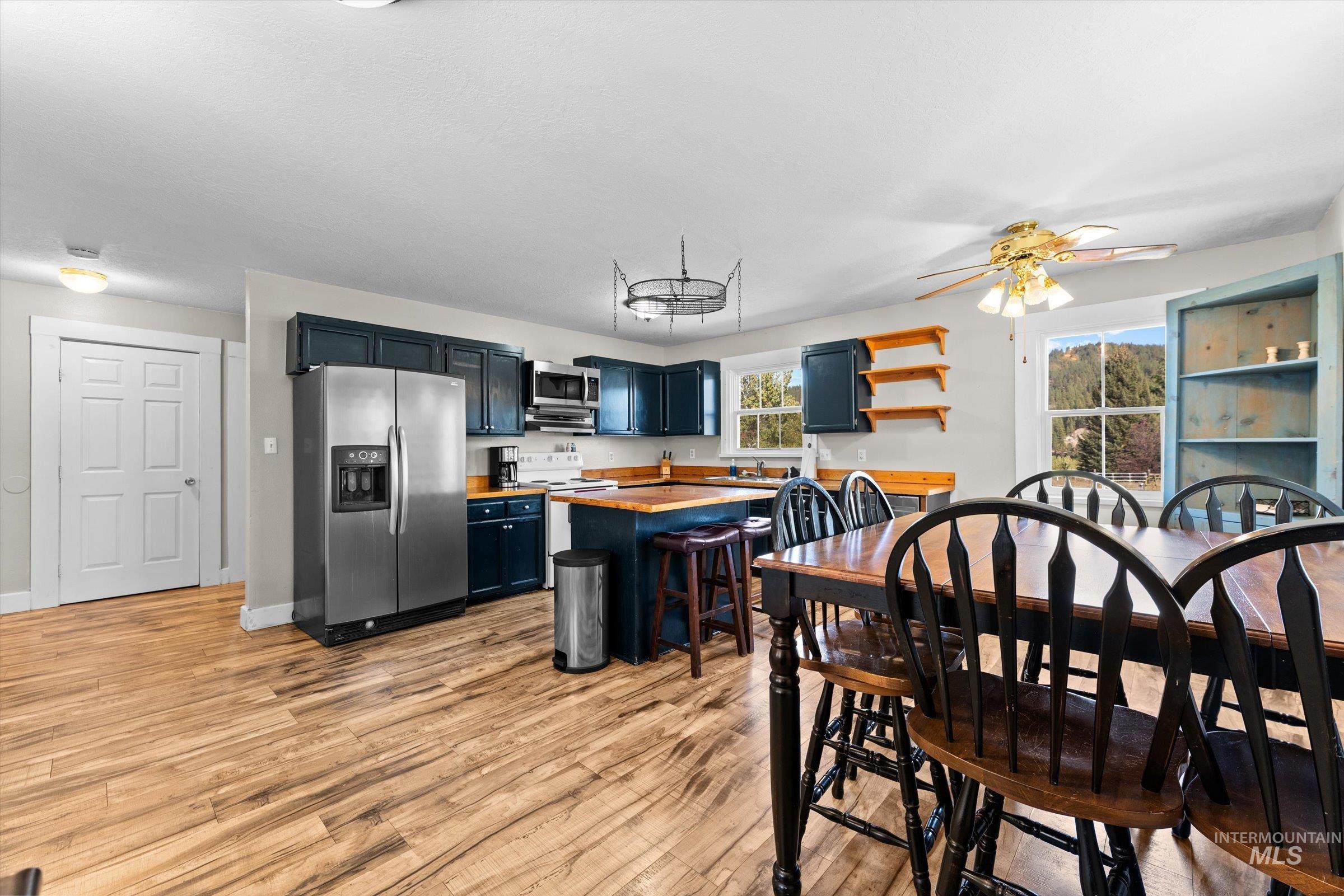 Kitchen with stainless steel appliances, butcher block counters, a breakfast bar, blue cabinets, and light wood finished floors