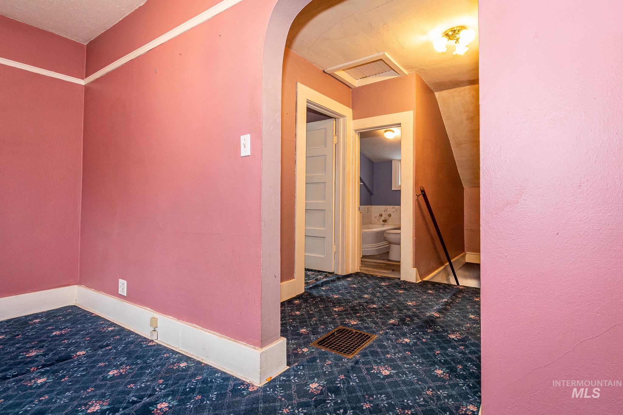 Hallway featuring an upstairs landing, arched walkways, and carpet flooring