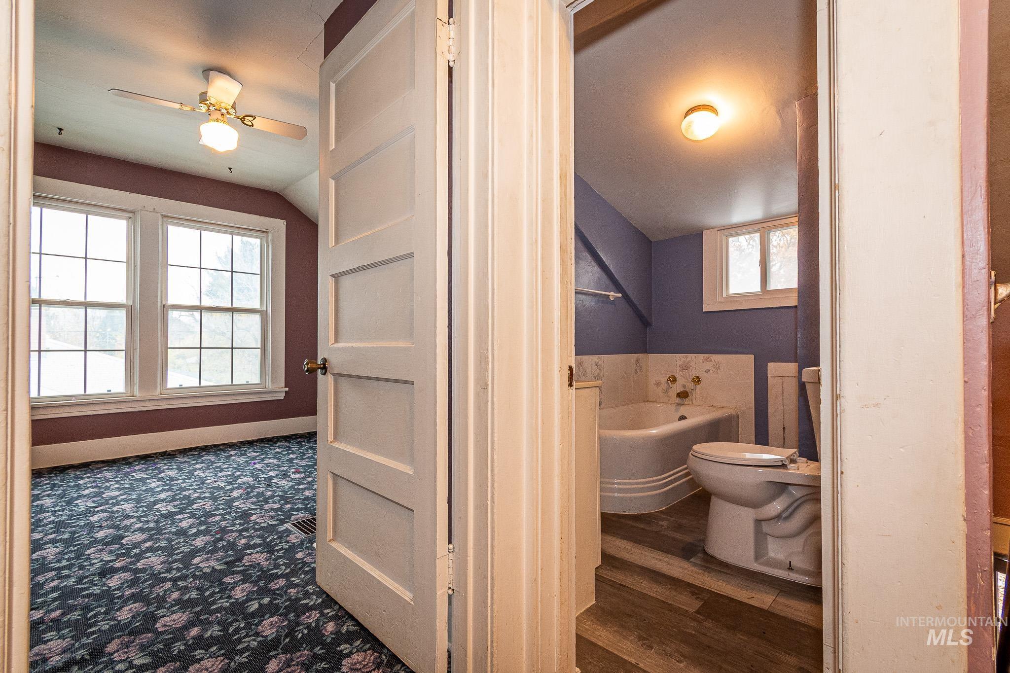 Bathroom with a bath, ceiling fan, lofted ceiling, and dark wood finished floors