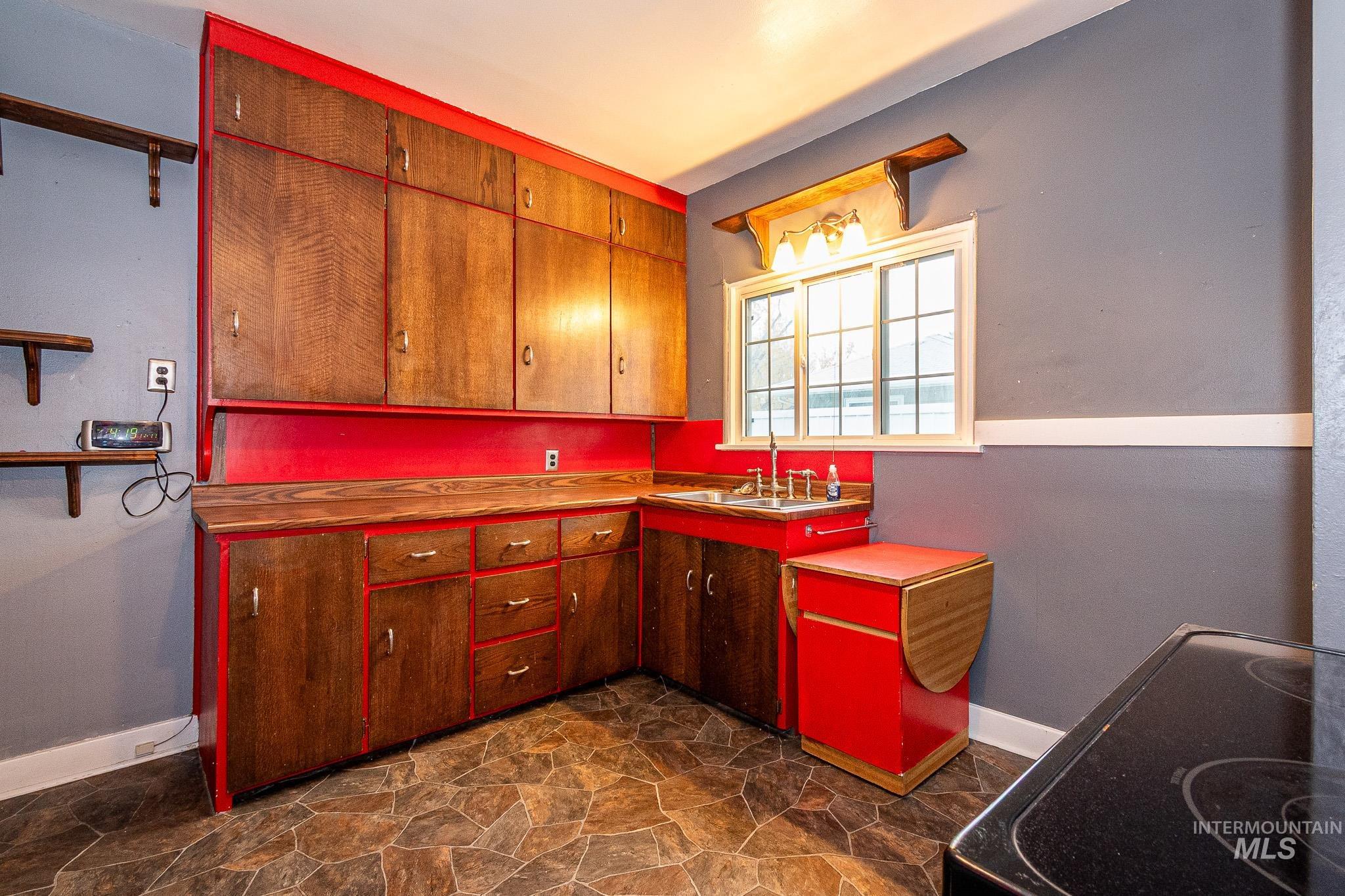 Kitchen featuring dark stone finish floors, black appliances, light countertops, and open shelves