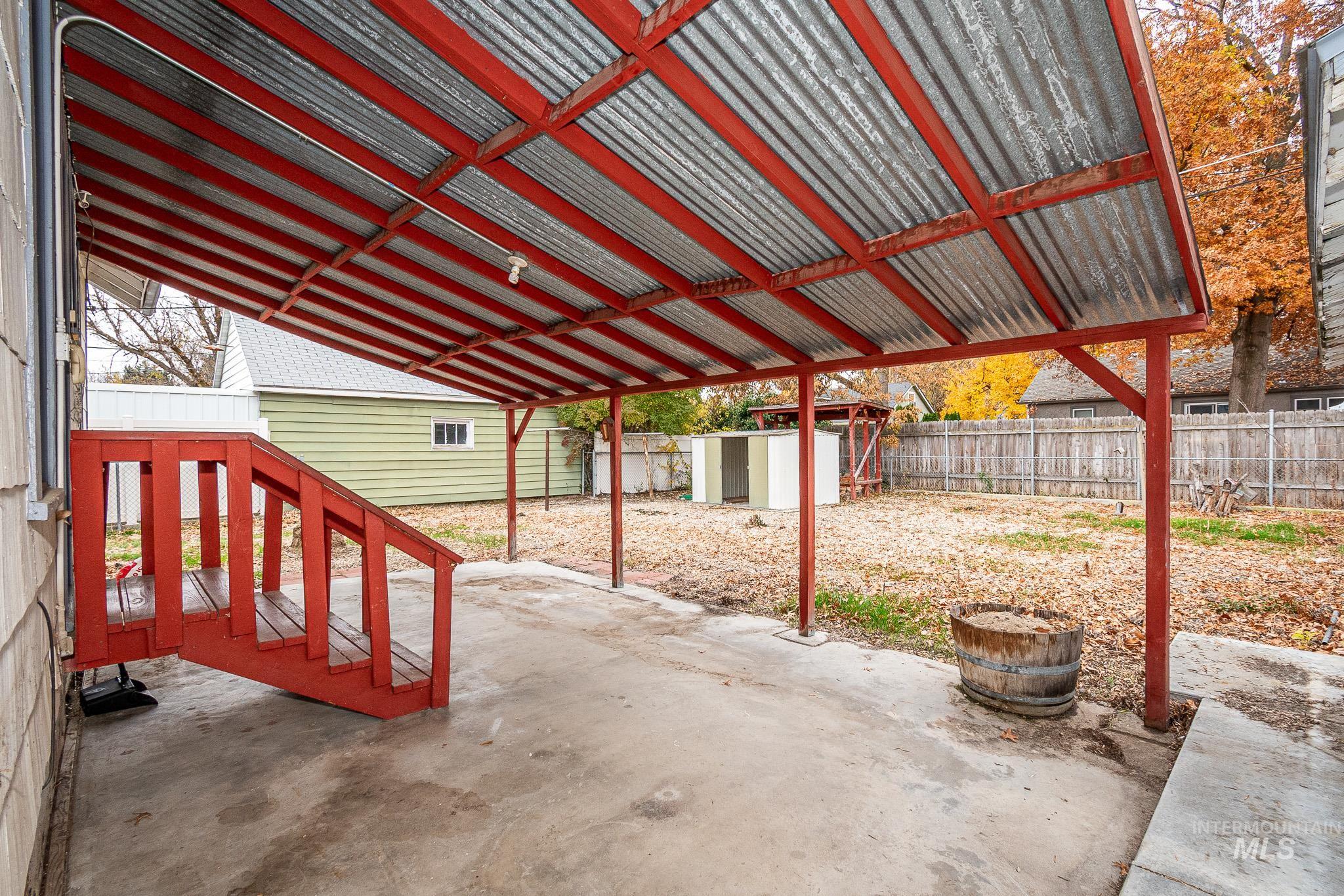Fenced backyard featuring a patio and a storage unit