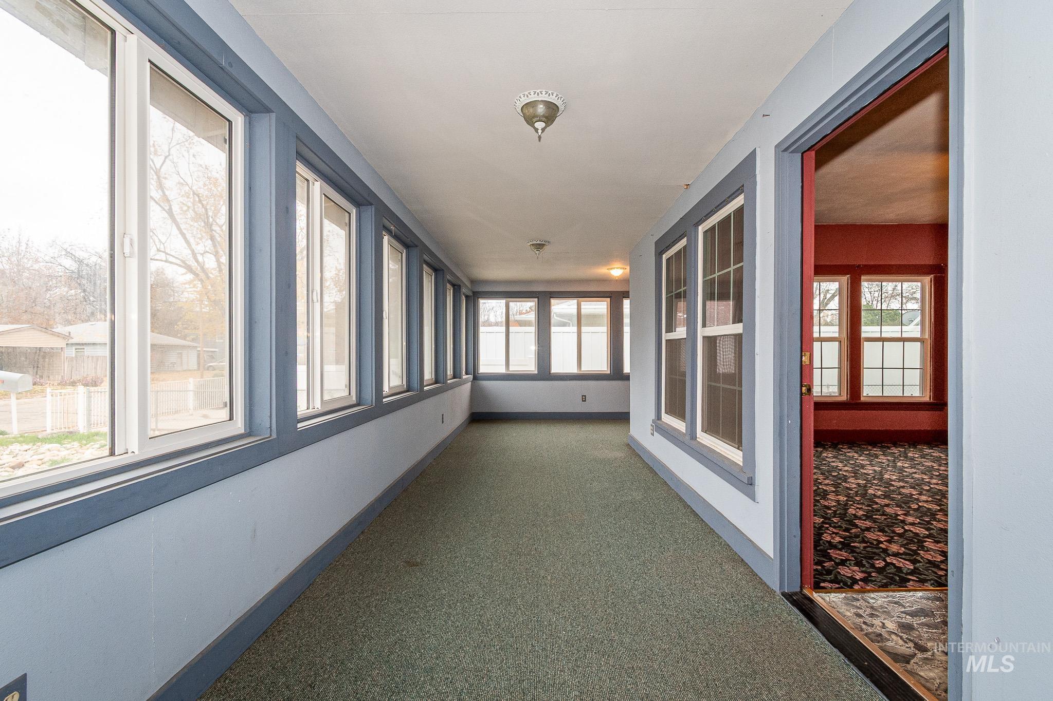 Unfurnished sunroom with baseboards and carpet floors