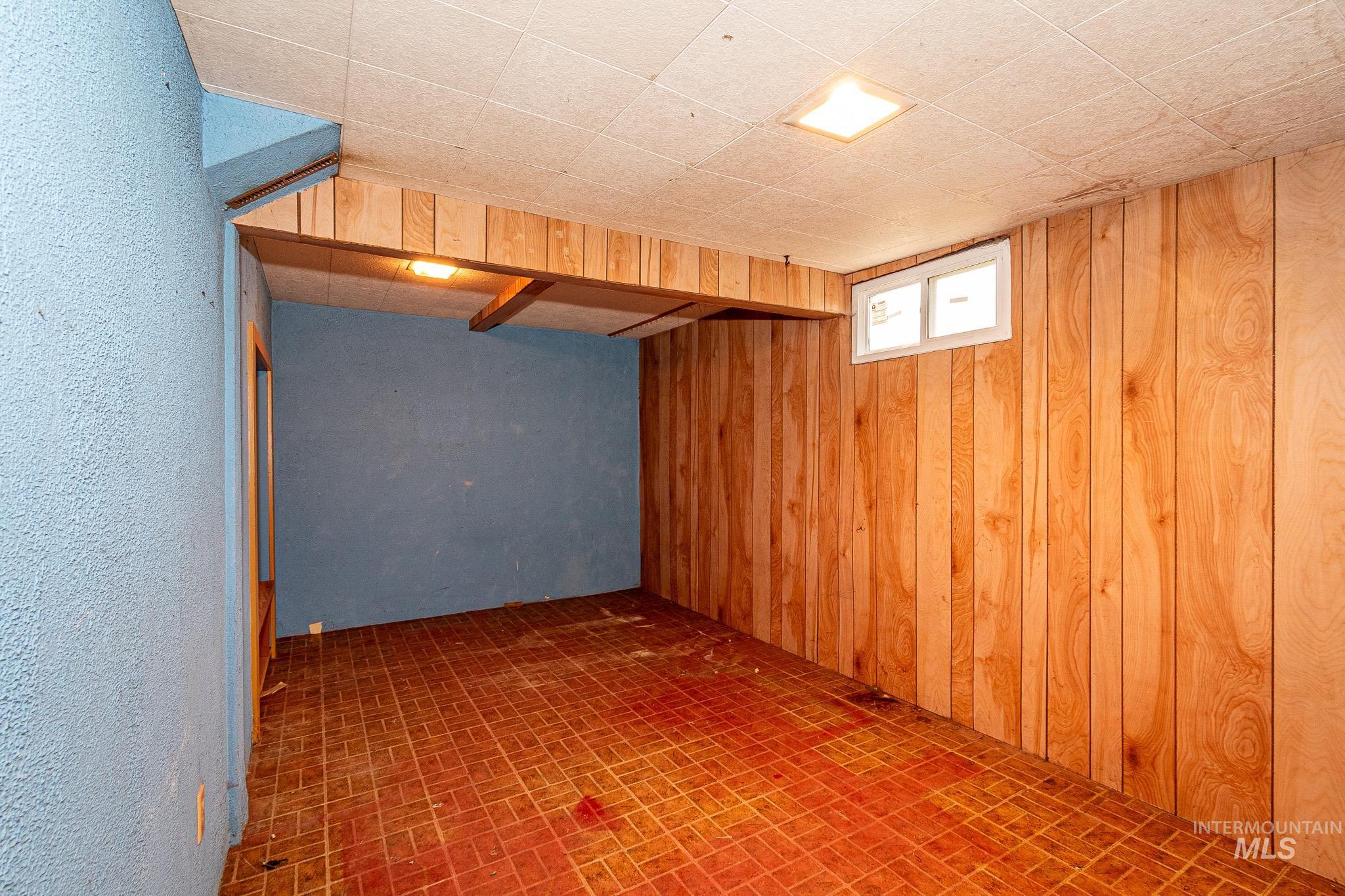 Below grade area featuring brick patterned floors and wood walls