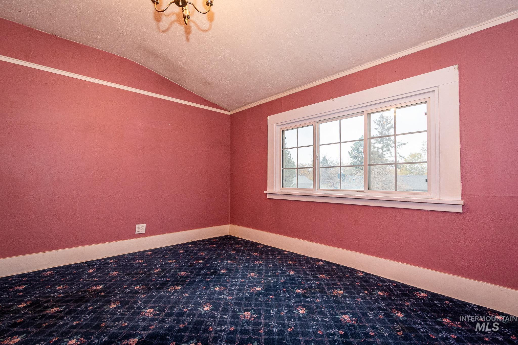 Empty room with lofted ceiling and crown molding