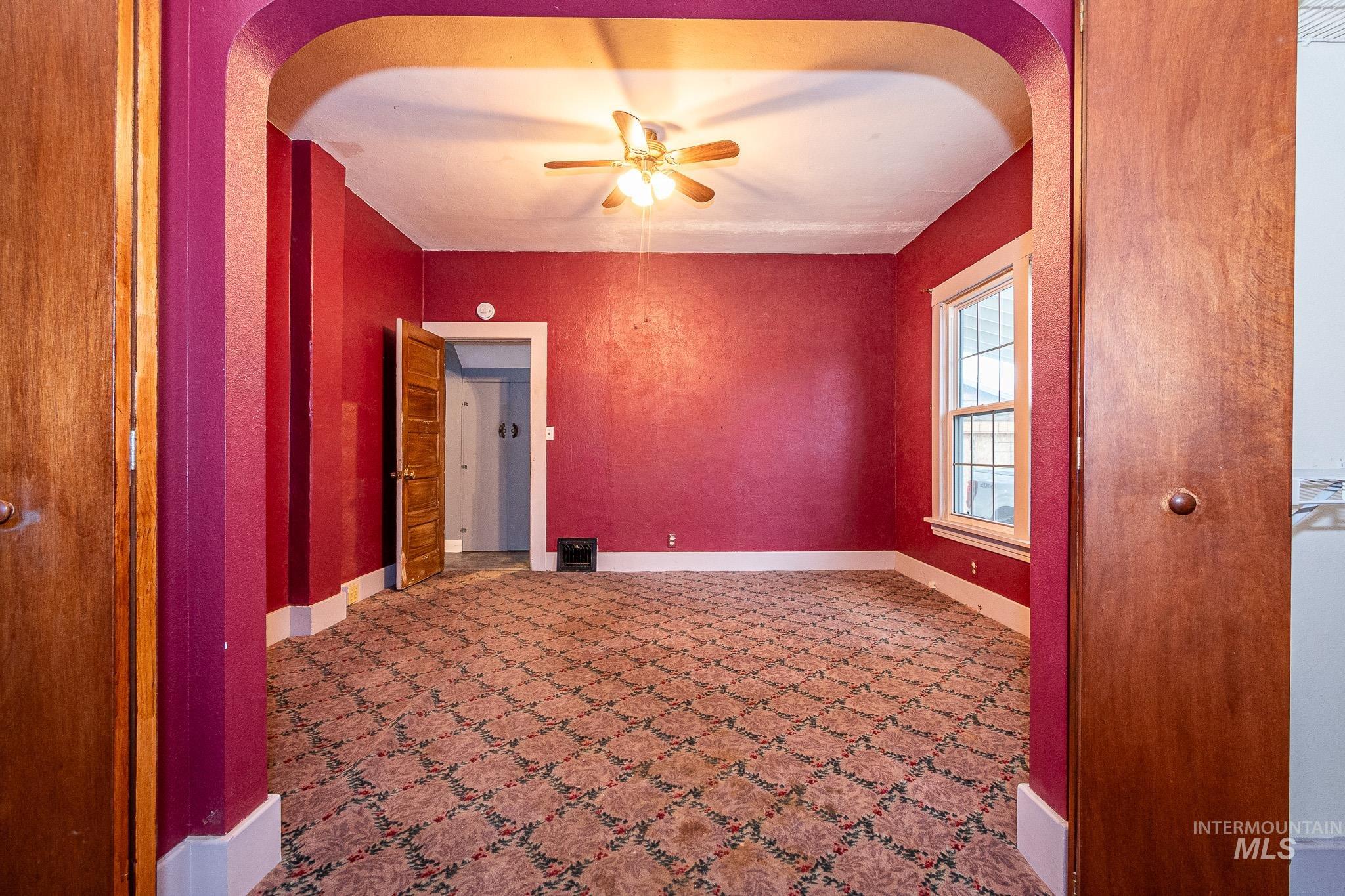 Unfurnished room featuring arched walkways and ceiling fan