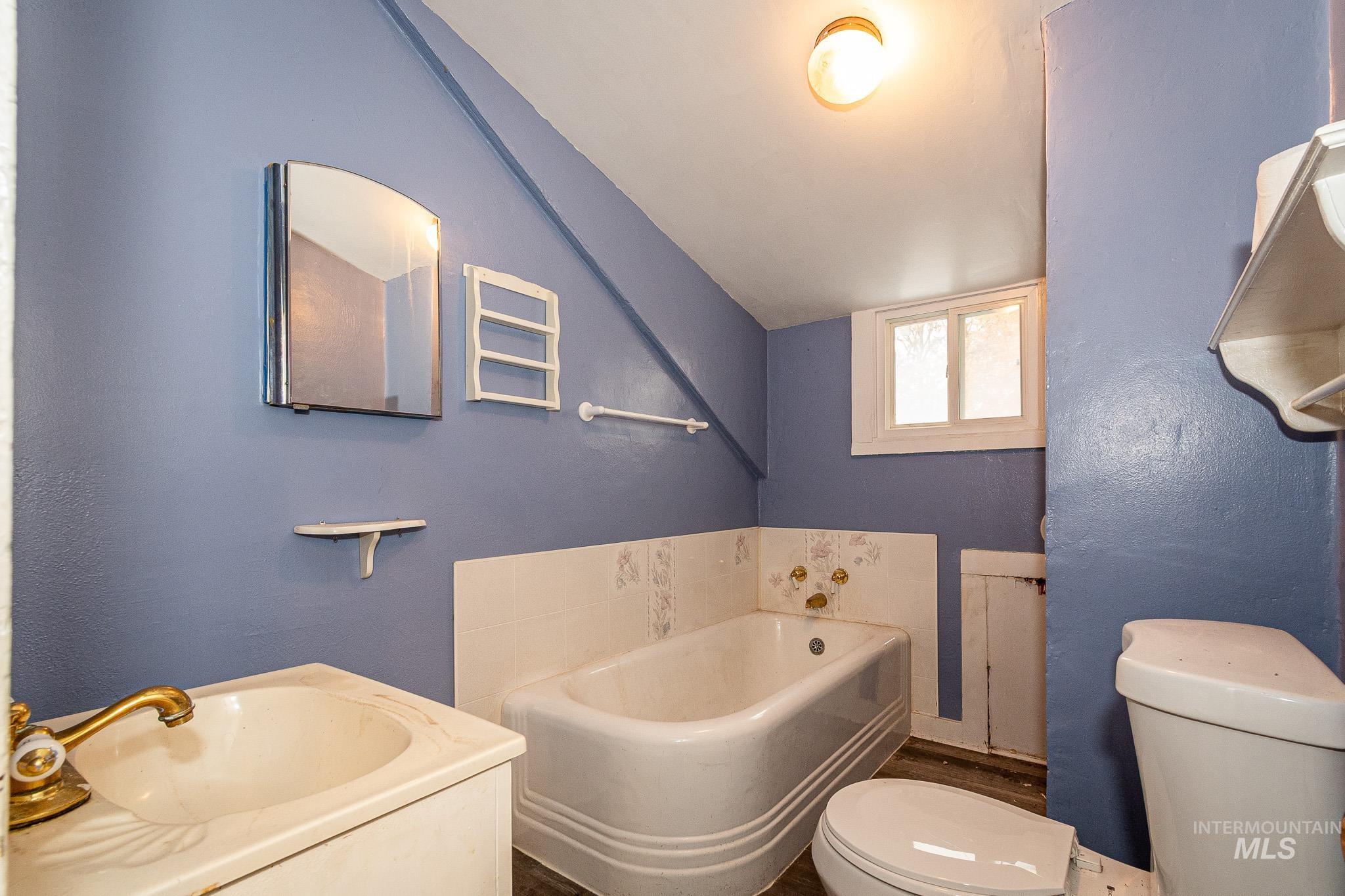 Full bath featuring a bath, vanity, and a textured wall