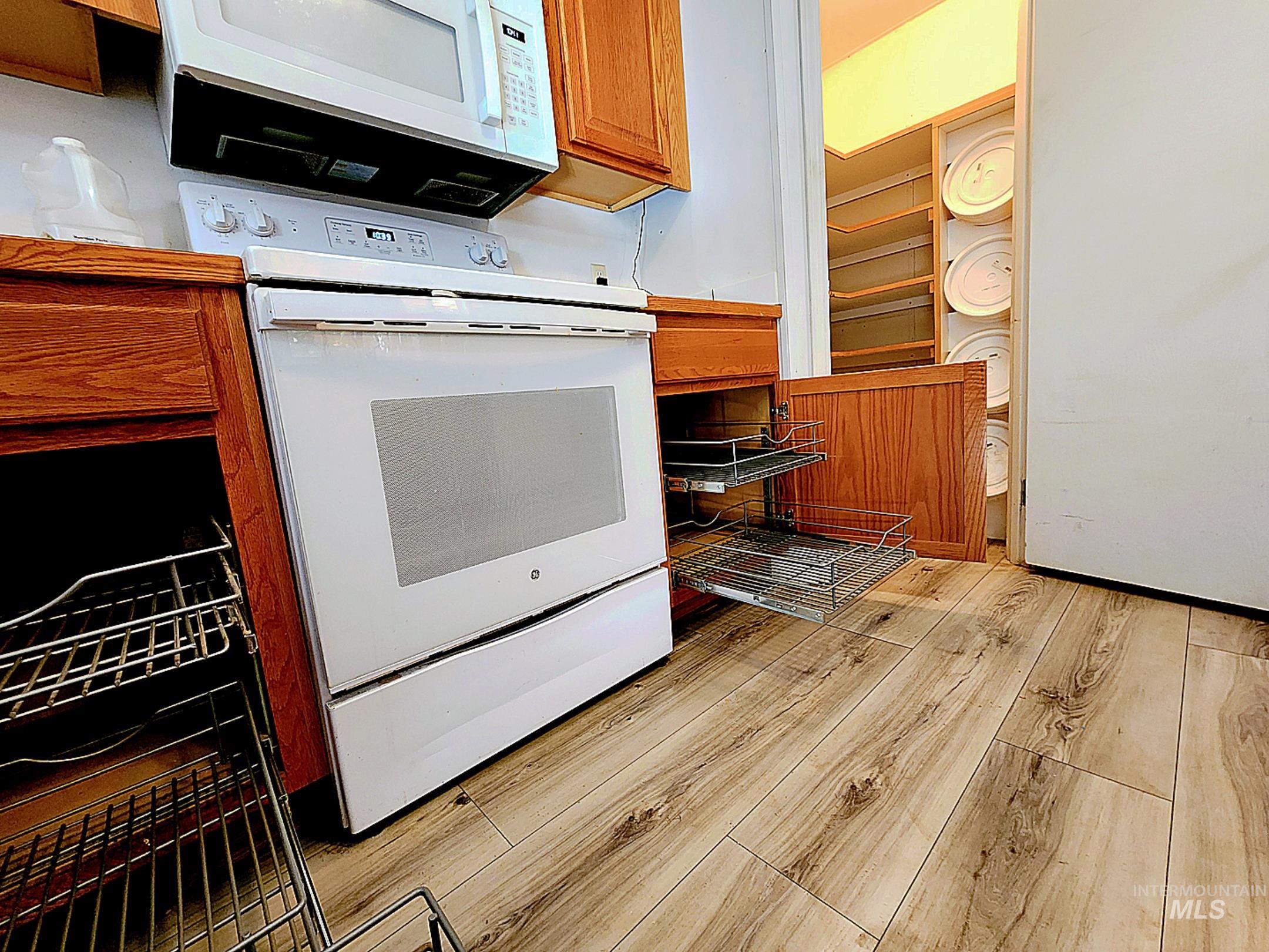 Inviting Idaho kitchen with pull-out cabinet shelves, wood cabinetry, and updated flooring offering a smart, functional design with modern appliances.