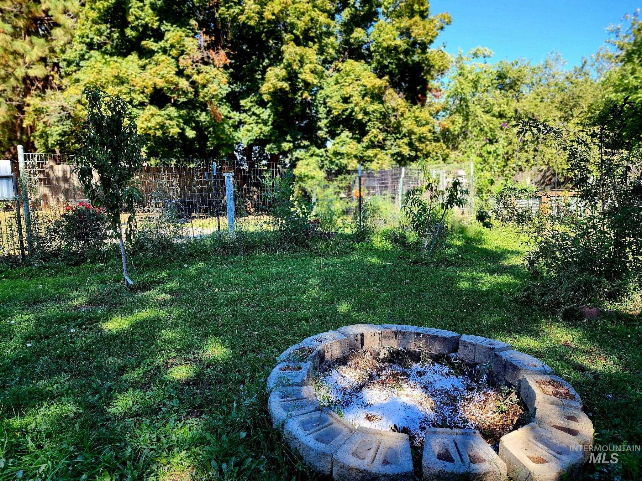 Enjoy evenings under the stars with a built-in fire pit, set against a spacious grassy yard and mature trees for a true Idaho outdoor retreat.