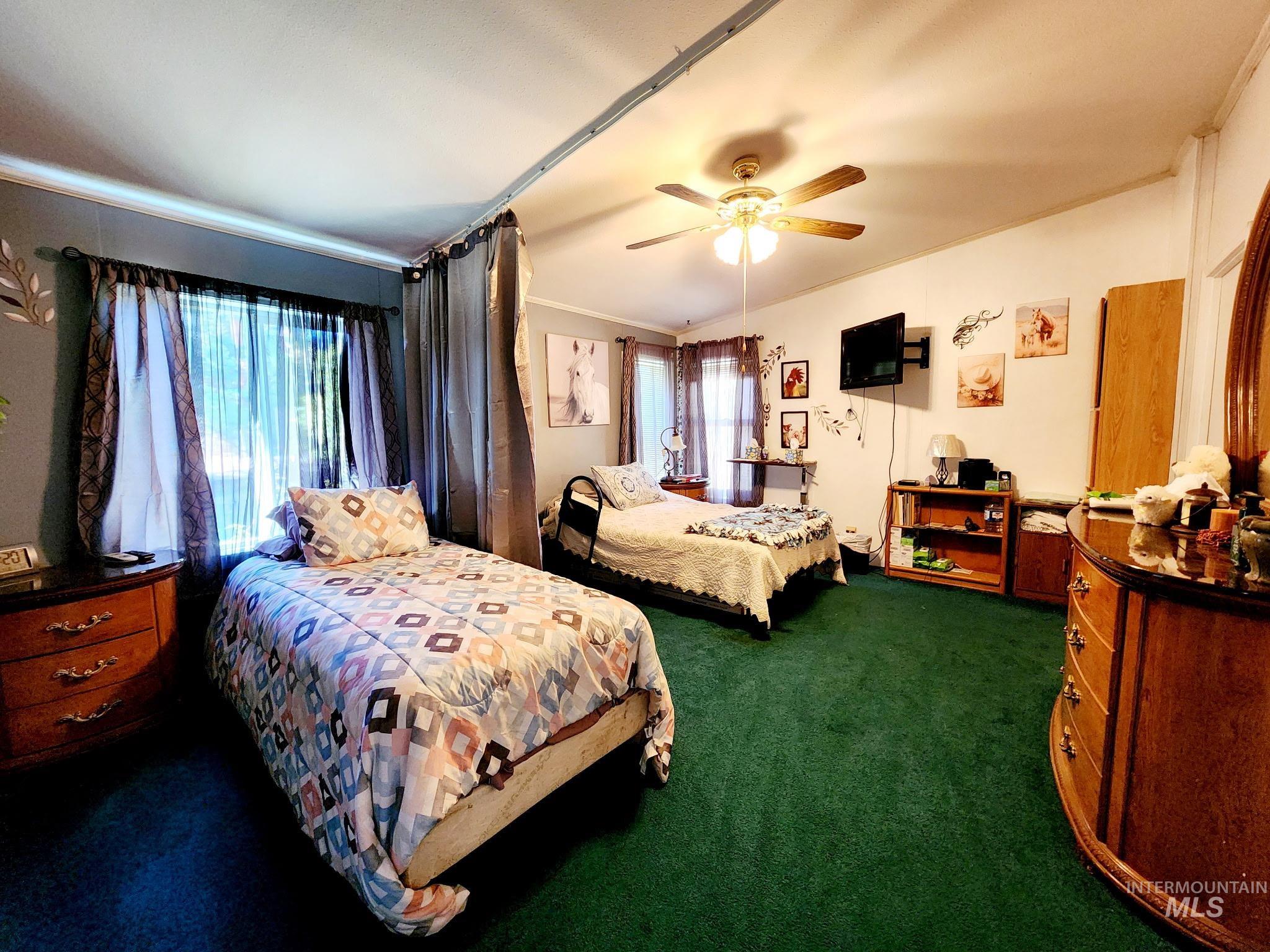 This spacious bedroom is set up with two sleeping areas, separated by a convenient divider curtain for added privacy. Large windows let in natural light.