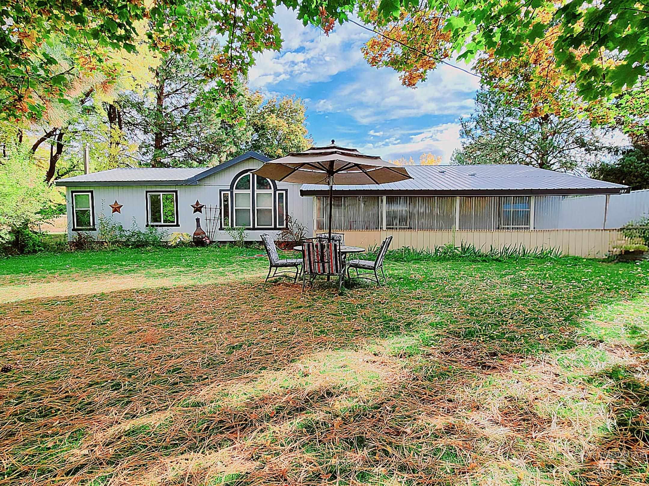 Idaho home for sale with a metal roof, screened porch, and beautiful mature trees offering a private yard and peaceful country charm.