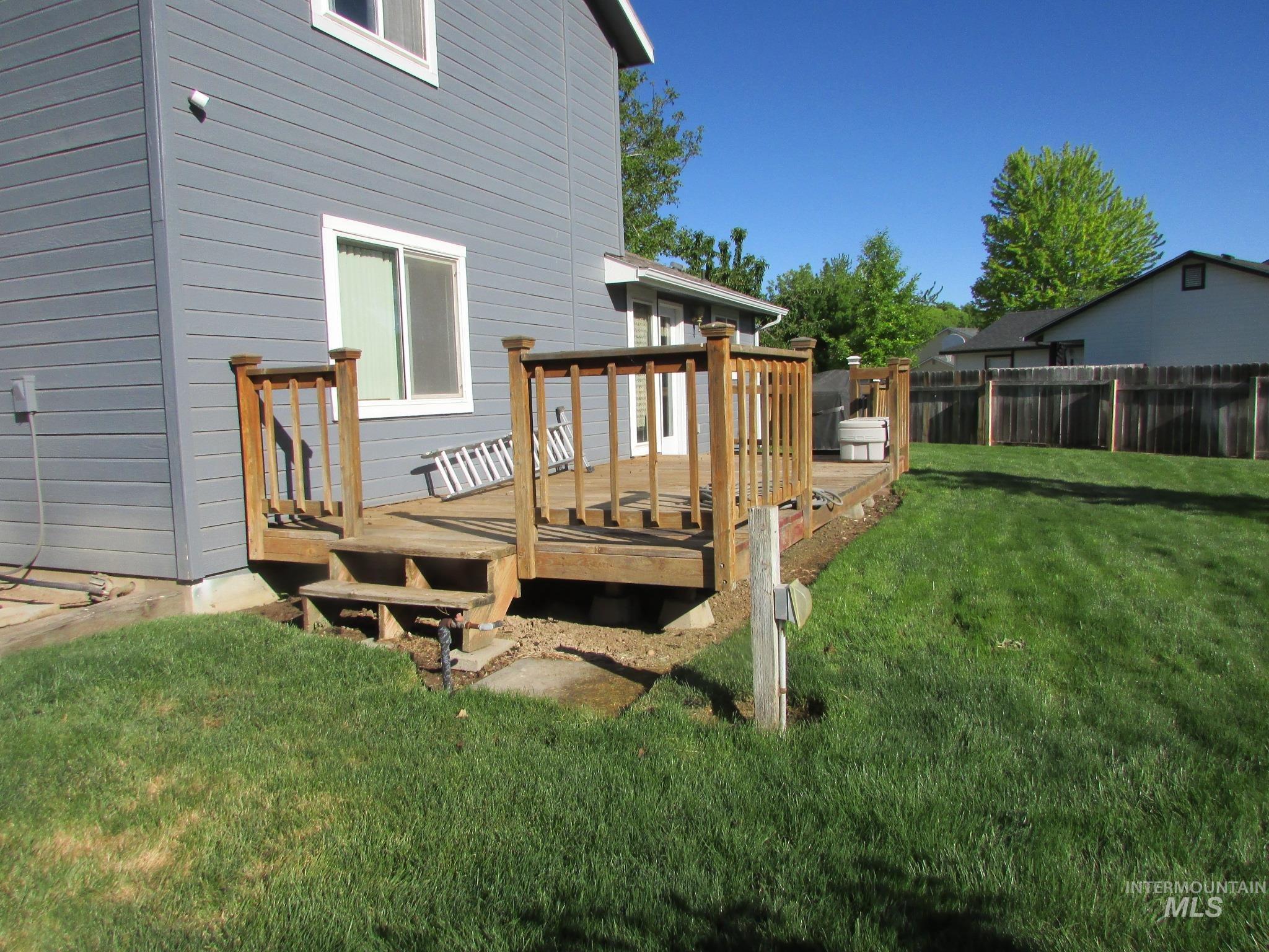 Expansive backyard featuring a wood deck with railings, a two-step entry, and a privacy fence