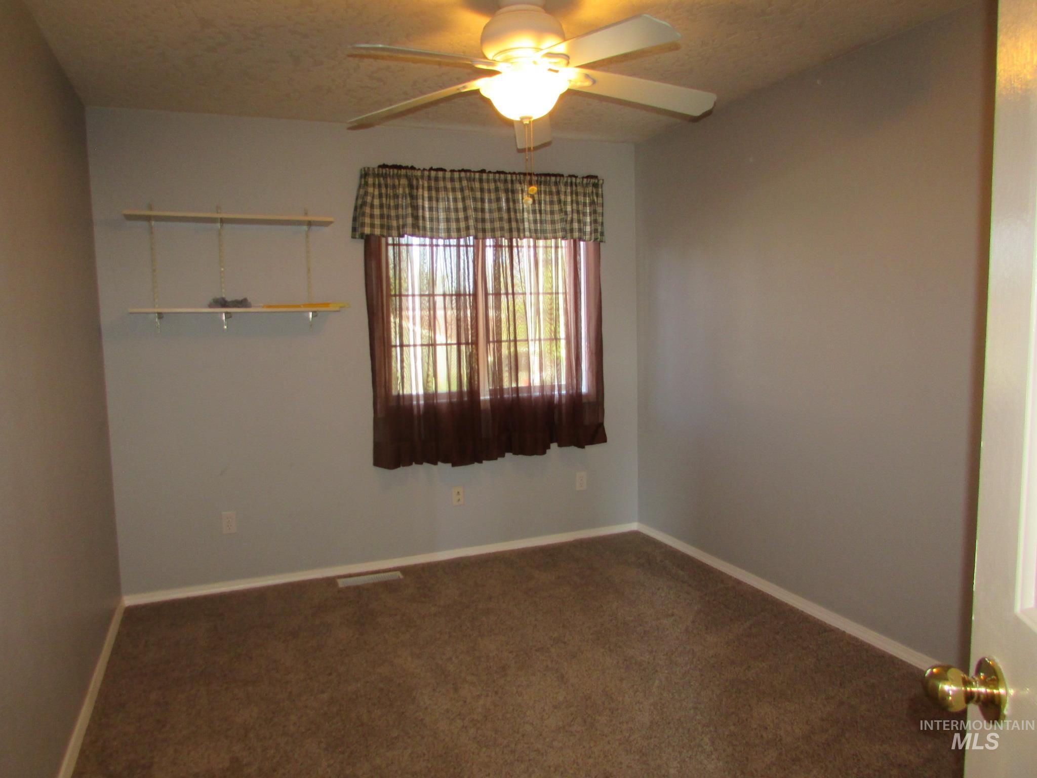 Inviting room featuring neutral wall paint, brown carpeting, and a ceiling fan with integrated lighting
