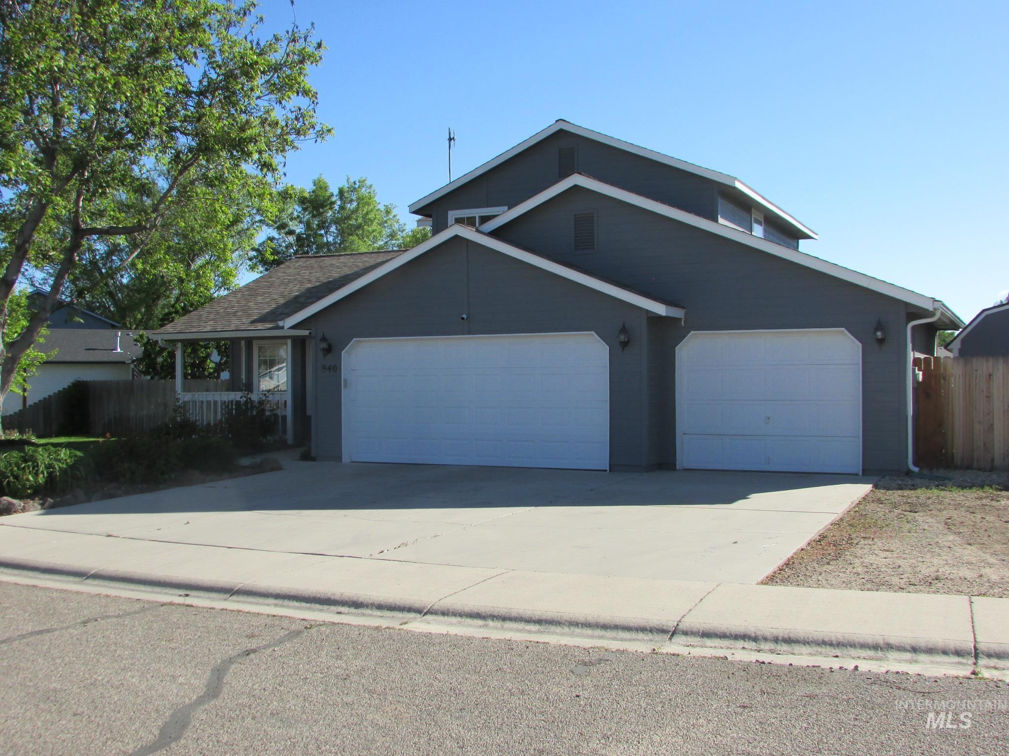 Two-story residence featuring a two-car garage with individual doors, a covered front porch with white railing, and a concrete driveway