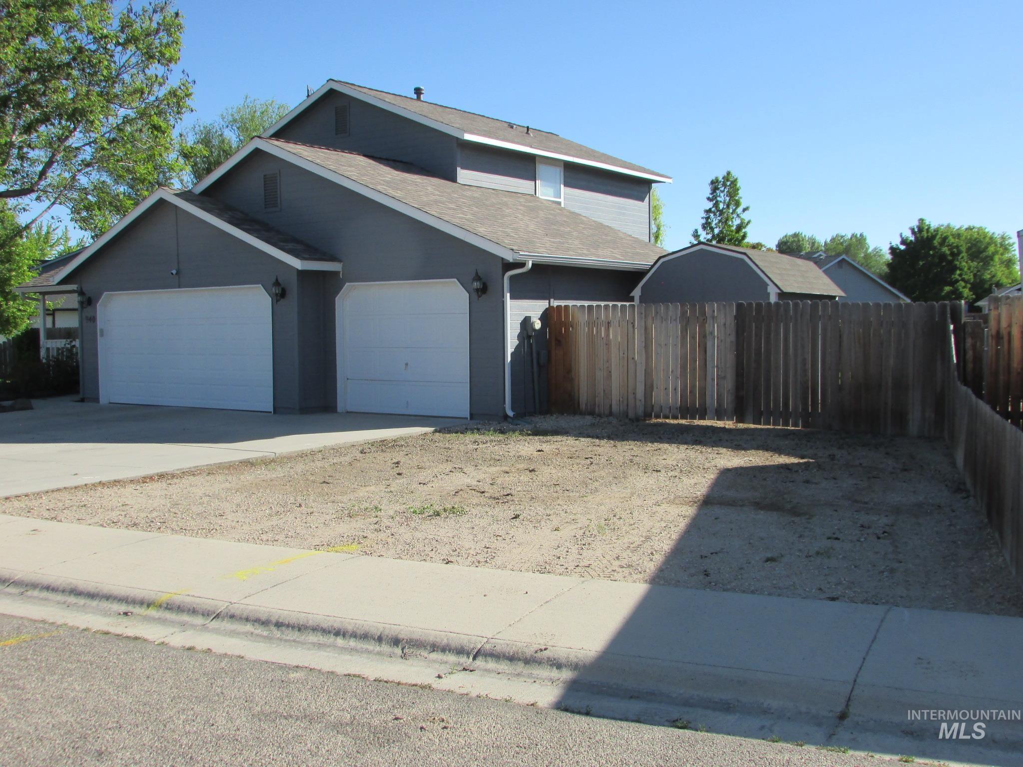 Two-story residence featuring a two-car garage with white doors, gray siding, and a light brown shingle roof