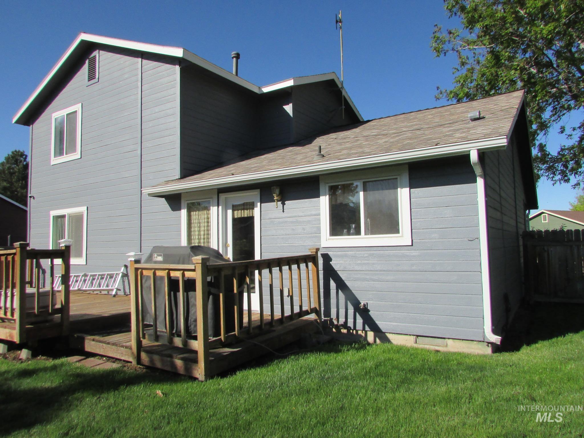 Exterior featuring gray horizontal siding, white trim, a brown shingle roof, white gutters, and a wood deck