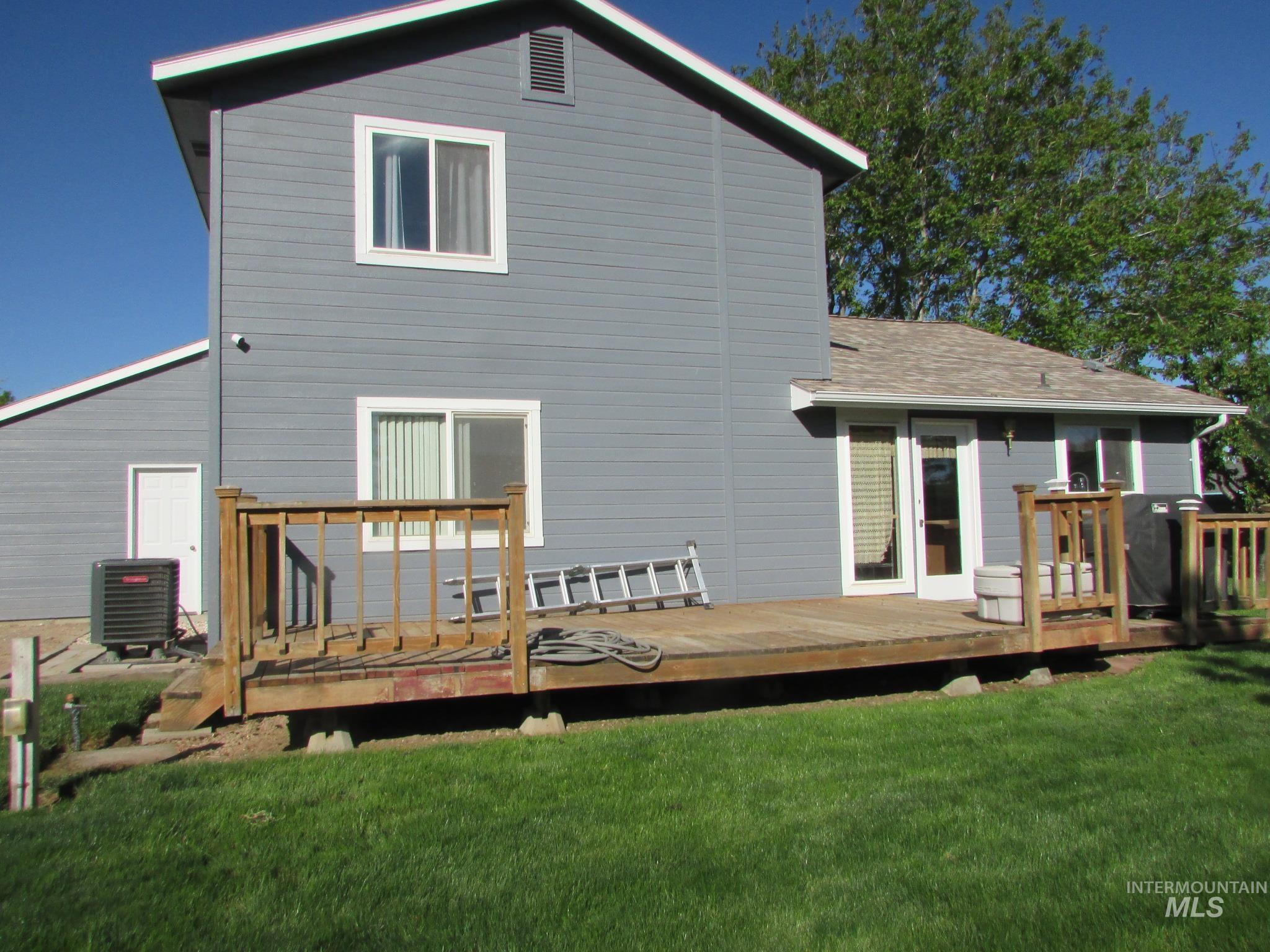 Rear exterior featuring a wood deck, grey horizontal siding, and white trim