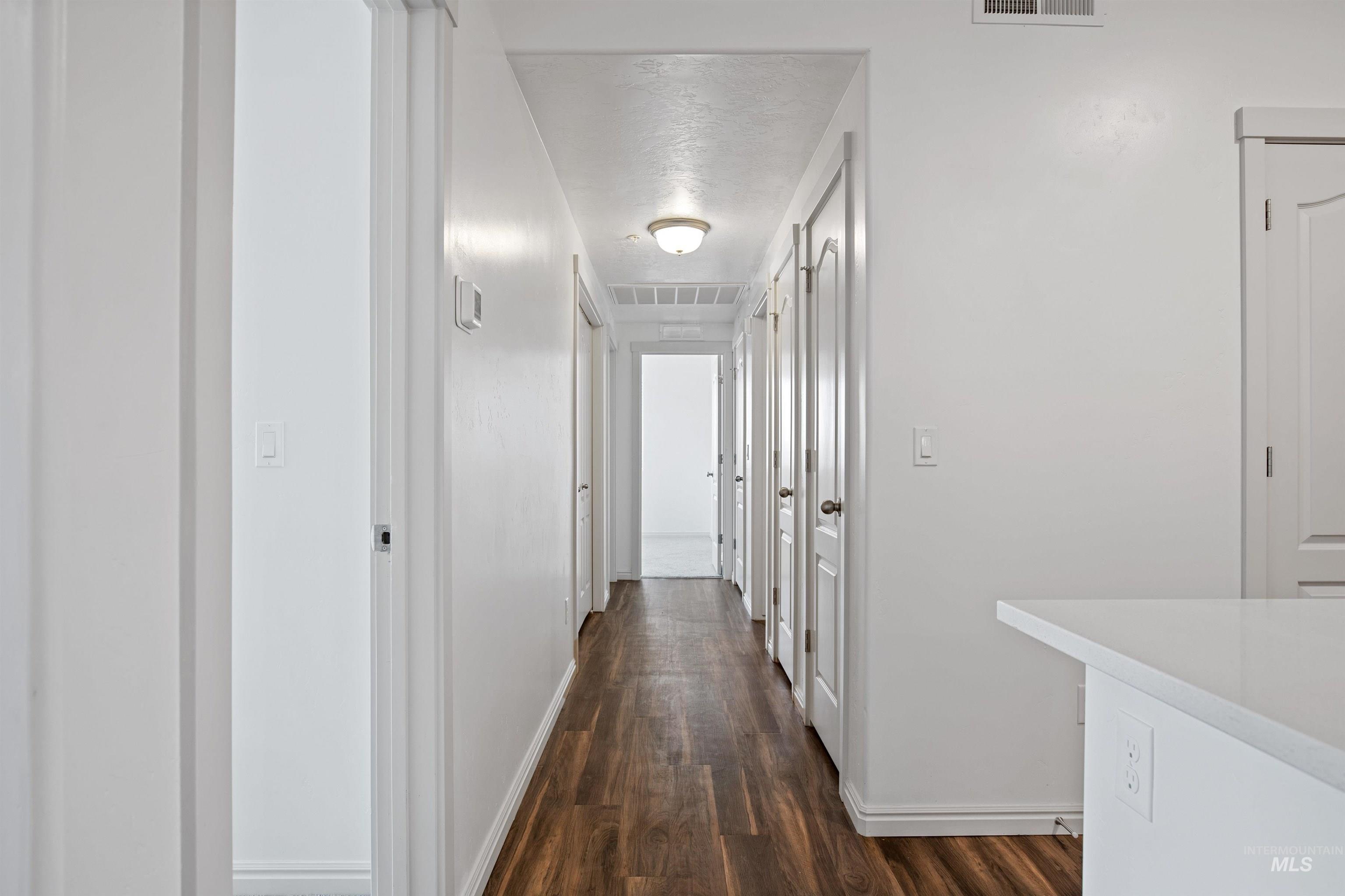 Corridor with dark wood-style floors and baseboards