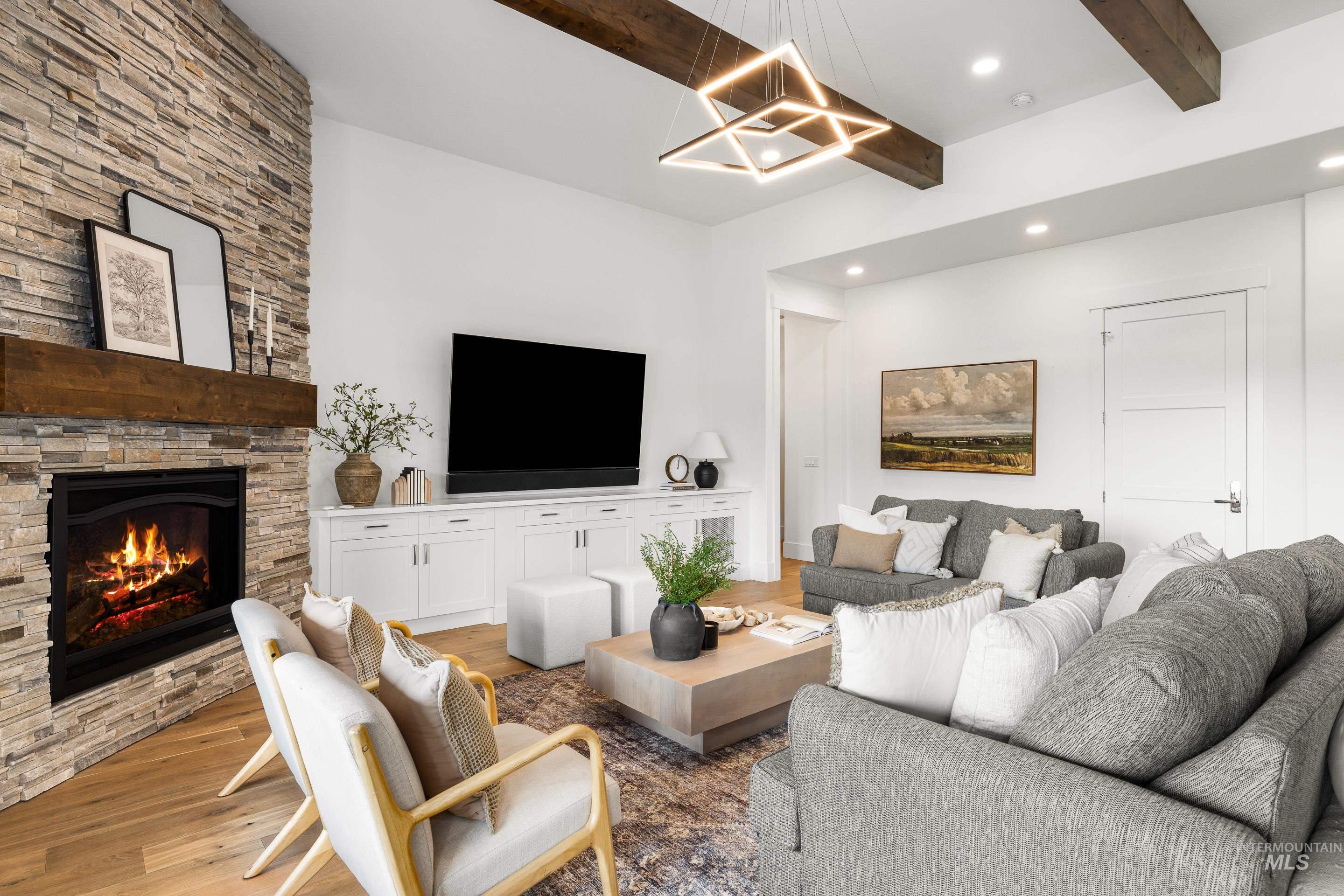 Living room with beamed ceiling, wood finished floors, recessed lighting, a fireplace, and a chandelier