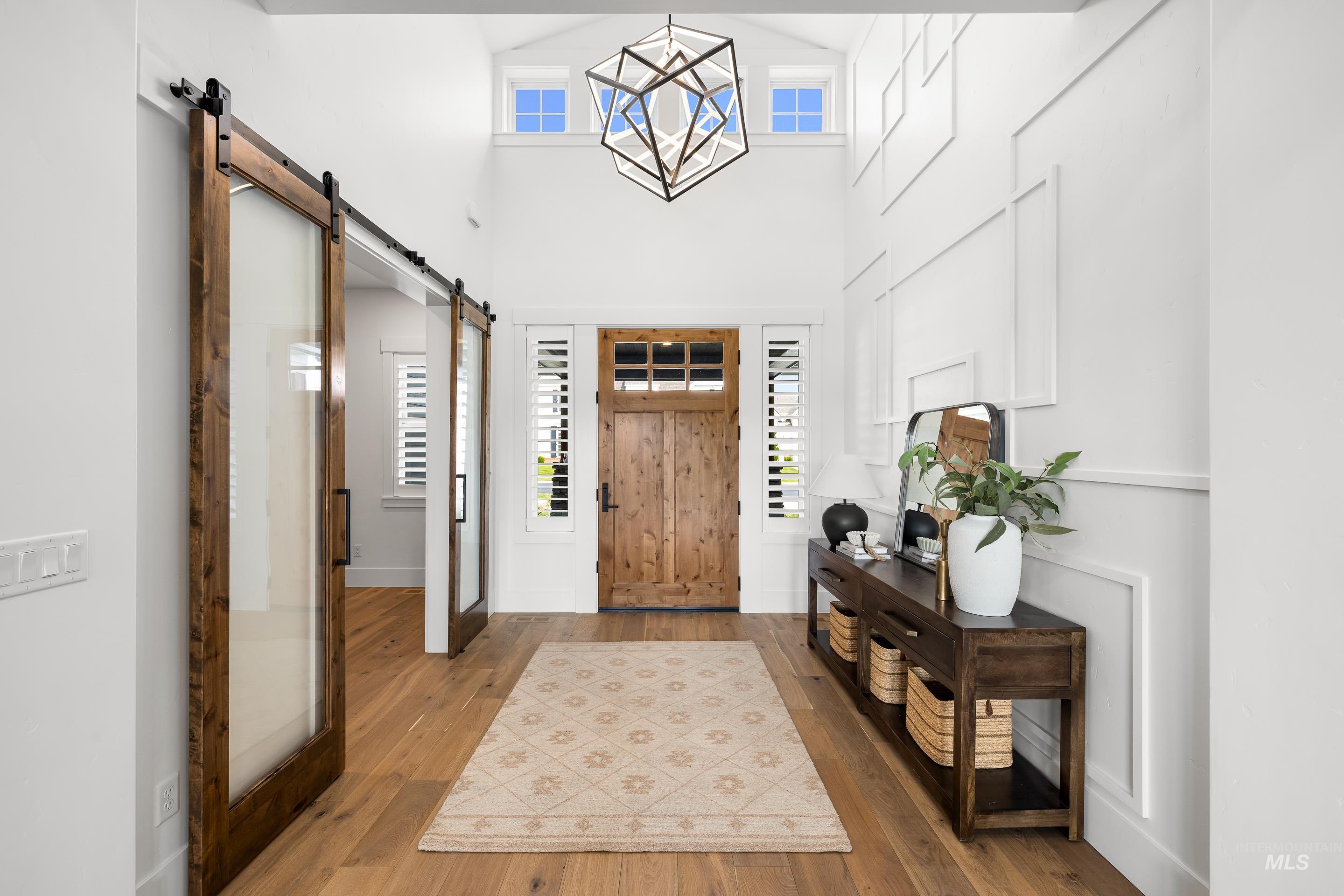 Foyer with a barn door, plenty of natural light, wood-type flooring, and a towering ceiling