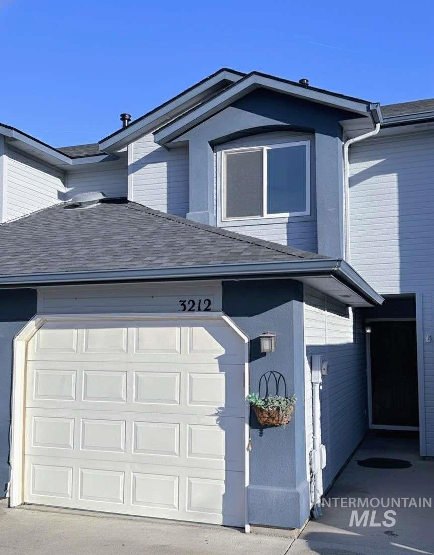 View of side of property with a garage and roof with shingles