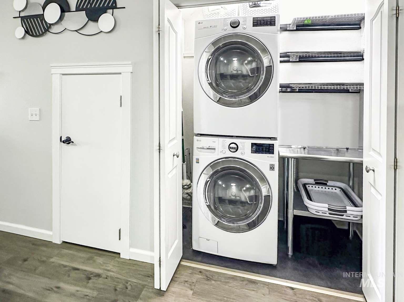 Laundry area with wood finished floors and stacked washing machine and dryer