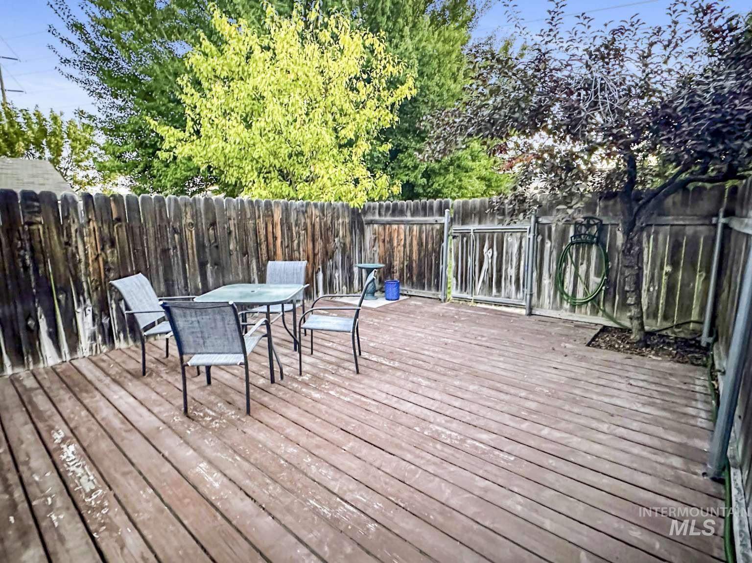 Wooden terrace featuring outdoor dining area and a fenced backyard