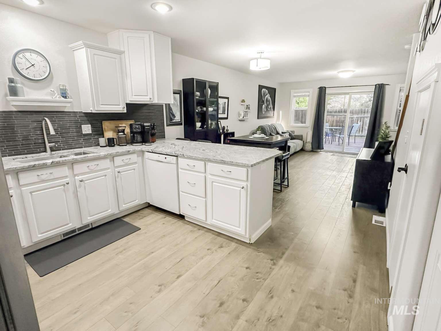 Kitchen with a peninsula, open floor plan, white cabinetry, and light wood-type flooring