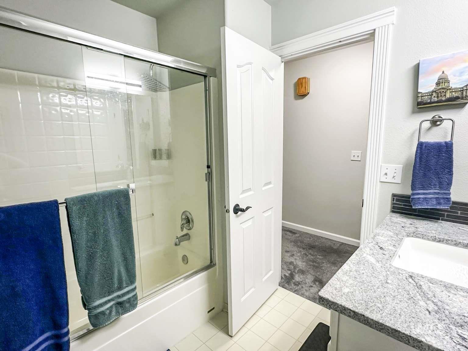 Bathroom with vanity, light tile patterned floors, and shower / bath combination with glass door