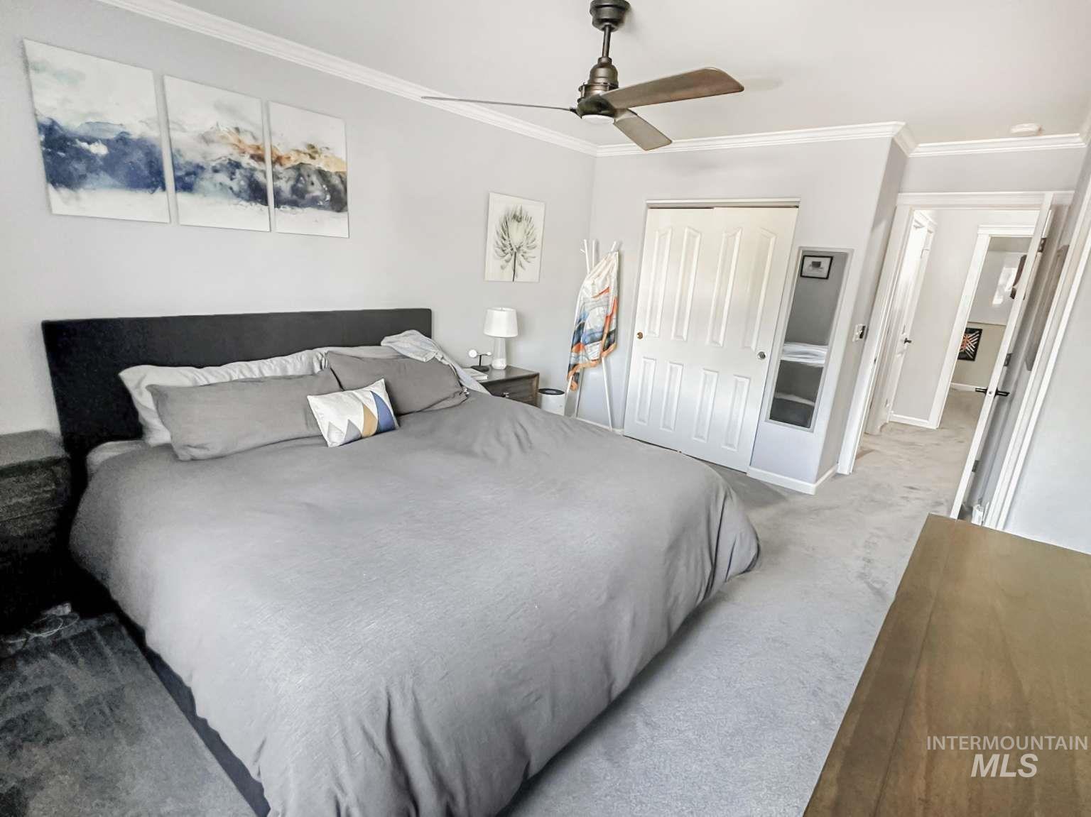 Bedroom featuring ornamental molding, light carpet, a closet, and a ceiling fan