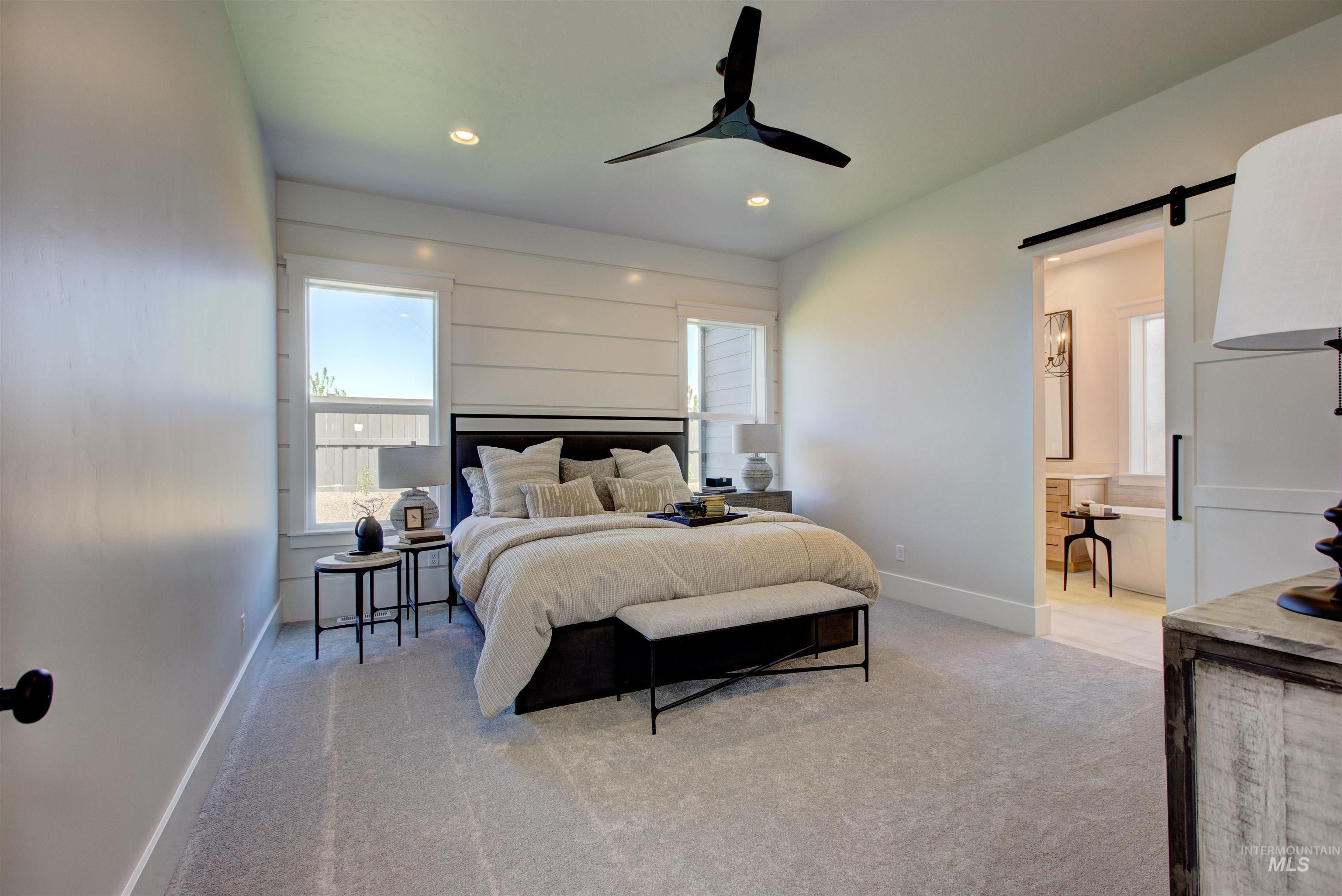 Bedroom with light carpet, a barn door, multiple windows, a ceiling fan, and recessed lighting