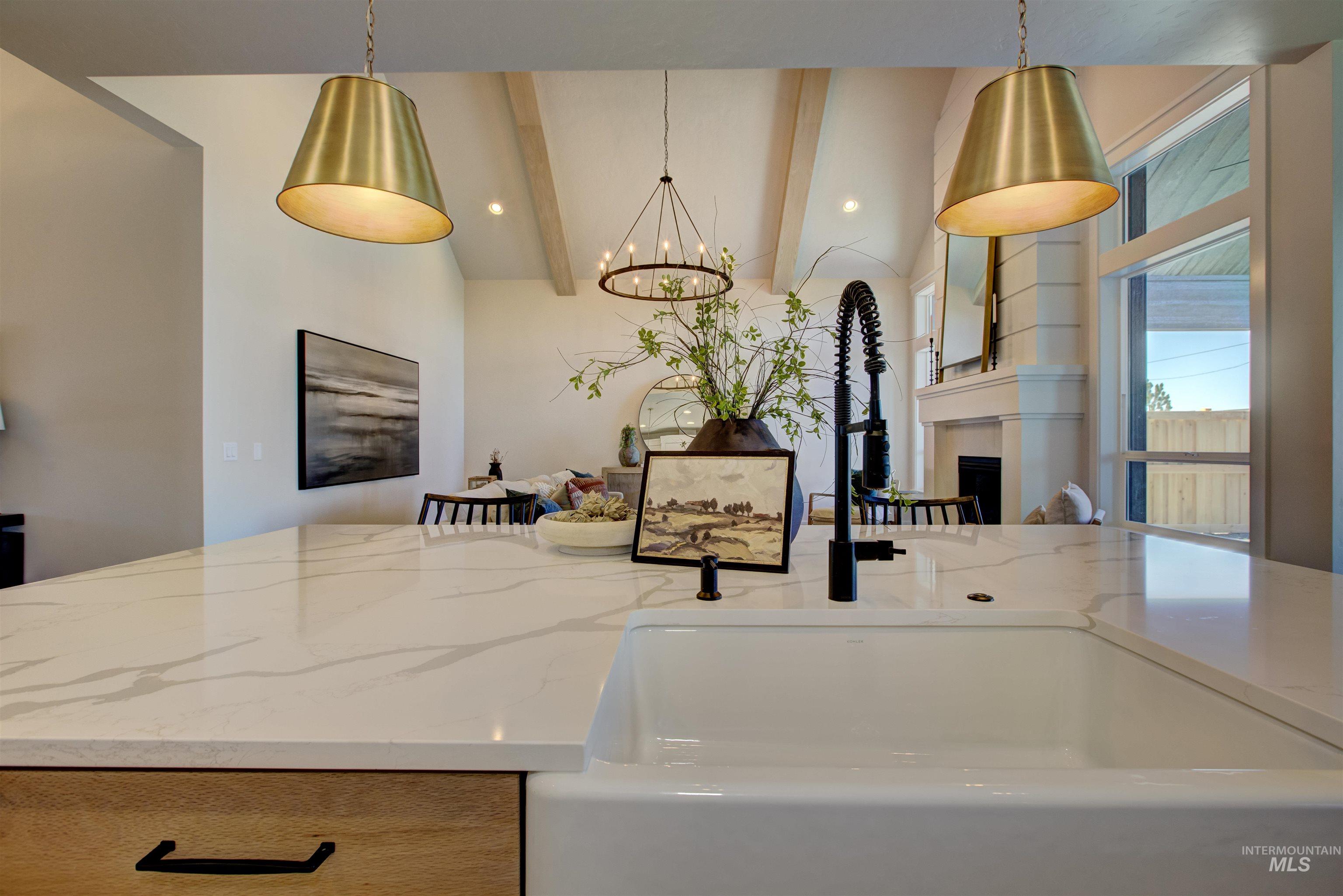 Kitchen with a fireplace, a chandelier, light stone counters, pendant lighting, and beam ceiling