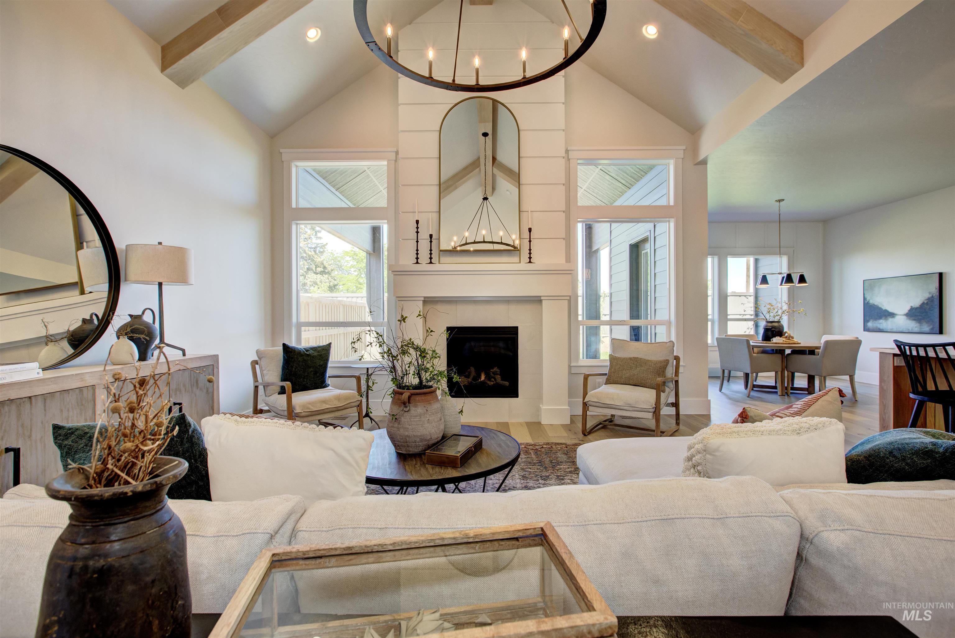 Living area with a tile fireplace, a chandelier, beam ceiling, wood finished floors, and high vaulted ceiling