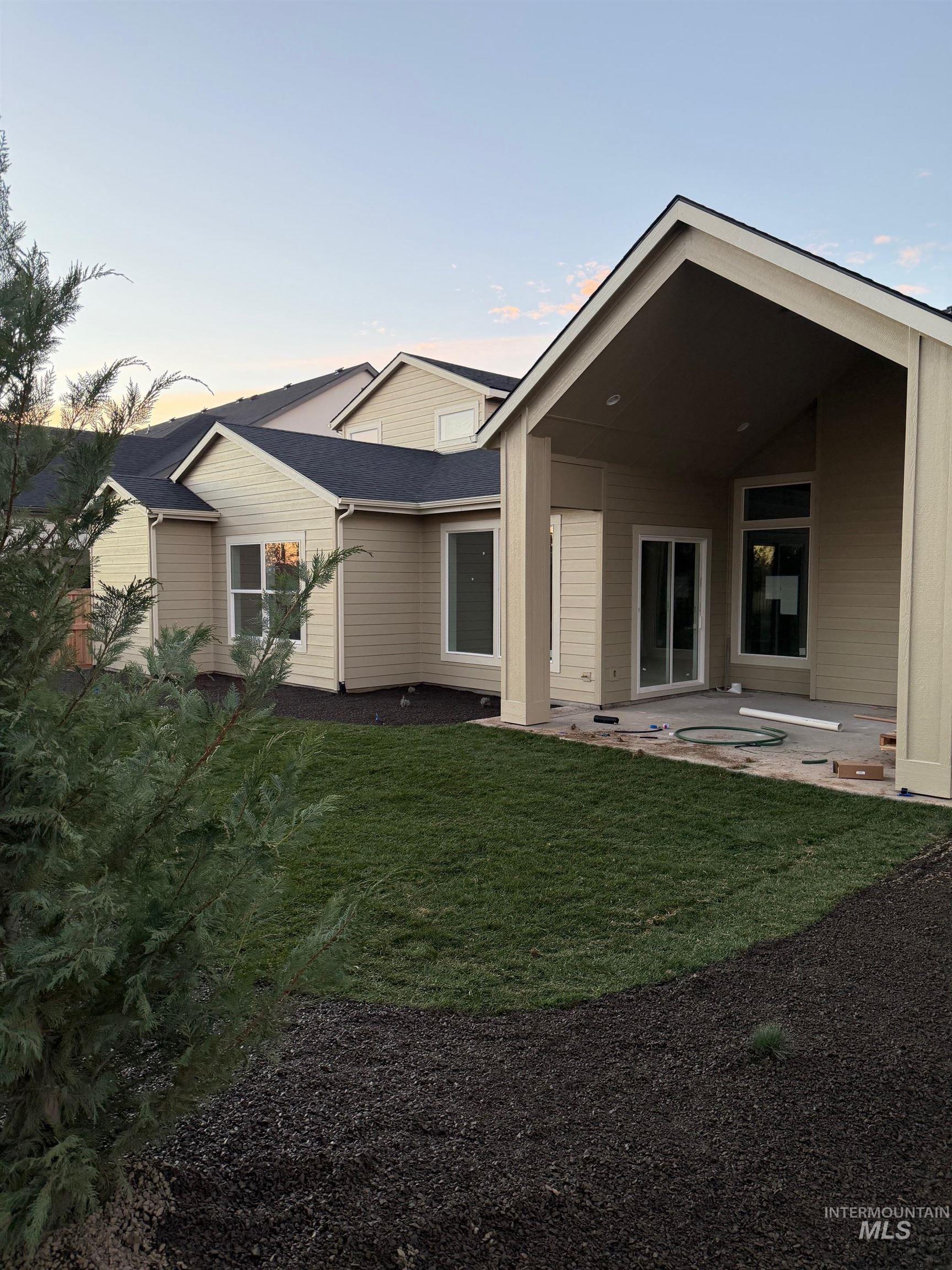 Back of property at dusk featuring a patio area and a yard