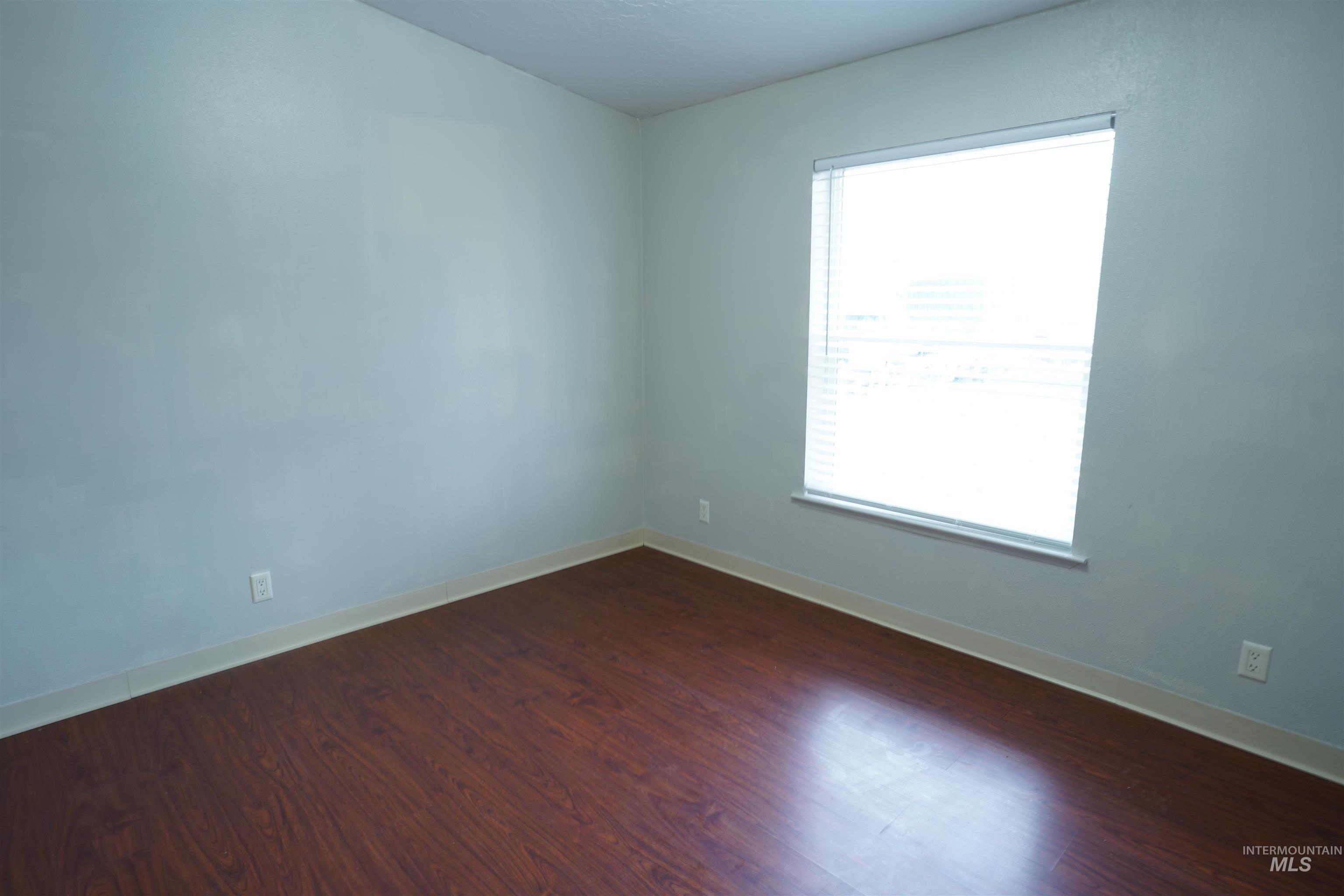Empty bedroom with dark wood-style floors and baseboards