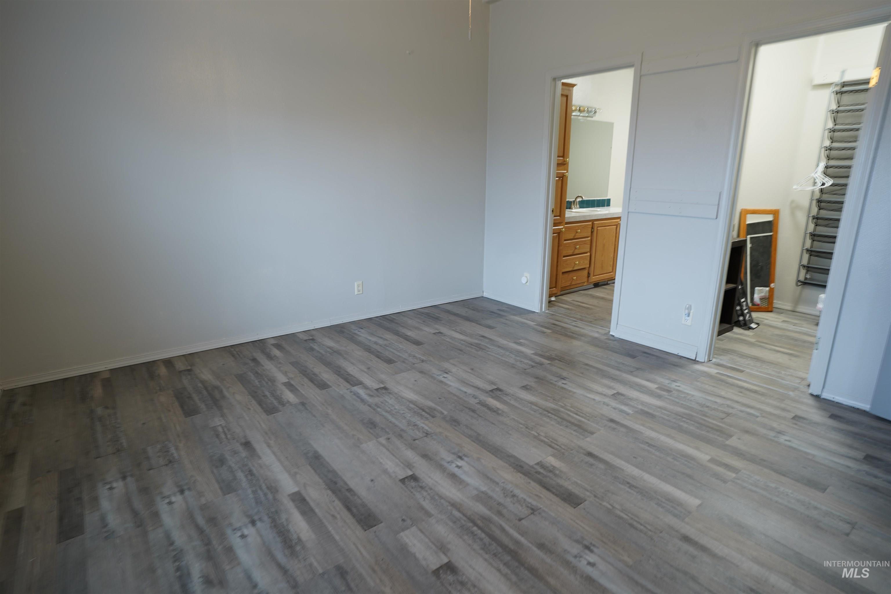 Unfurnished bedroom featuring a walk in closet, wood finished floors, and ensuite bathroom