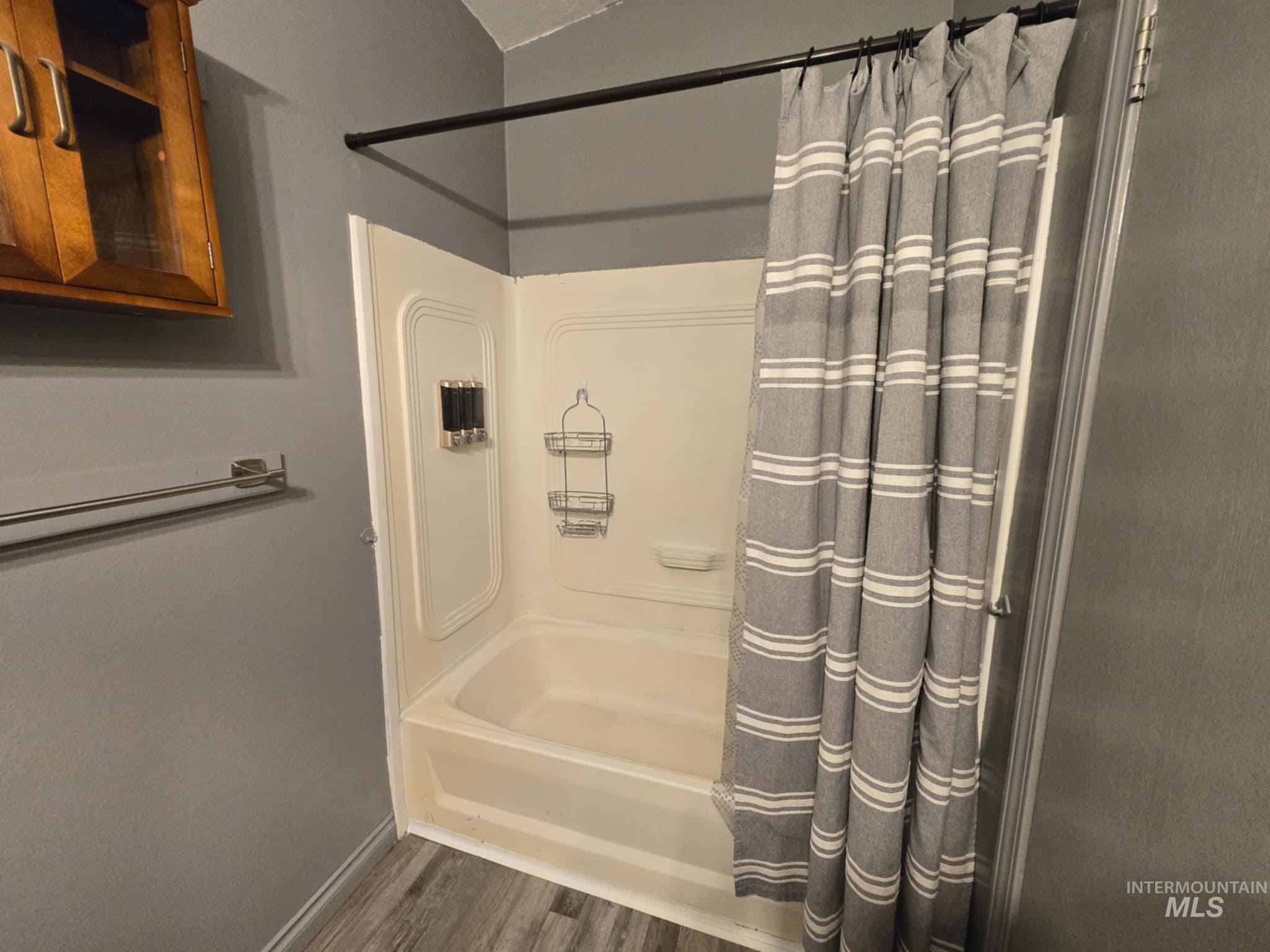 Bathroom featuring dark wood-style flooring and shower / tub combo