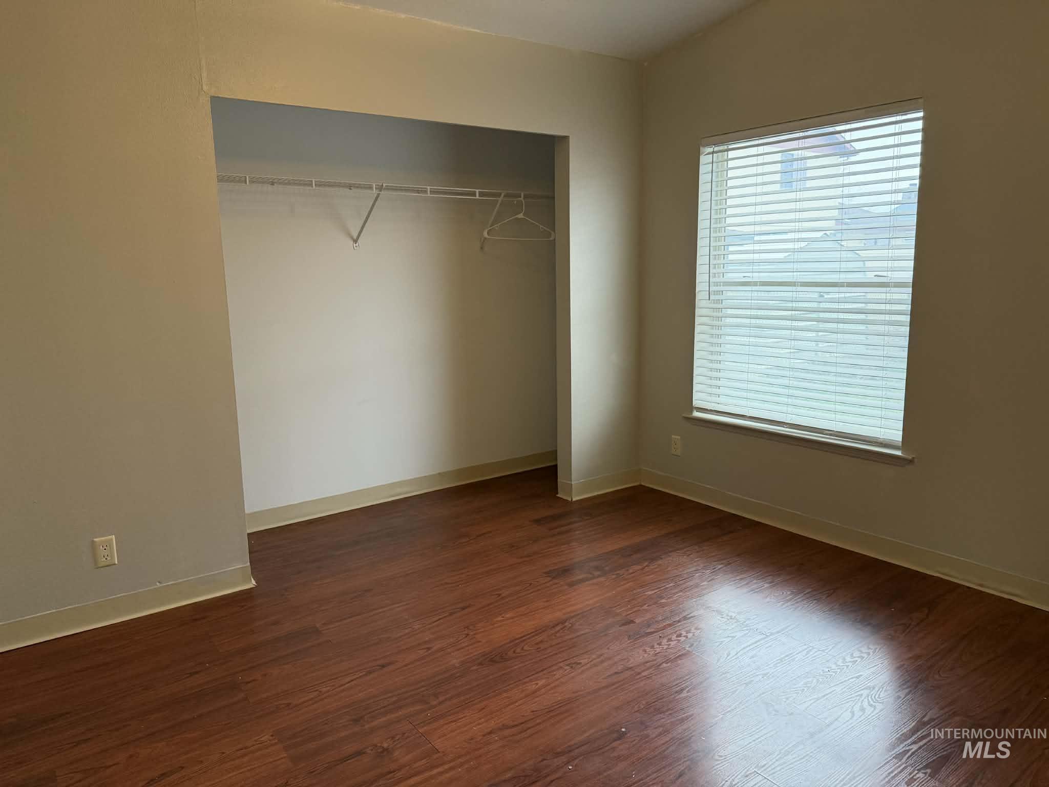 Unfurnished bedroom with dark wood-style floors and a closet