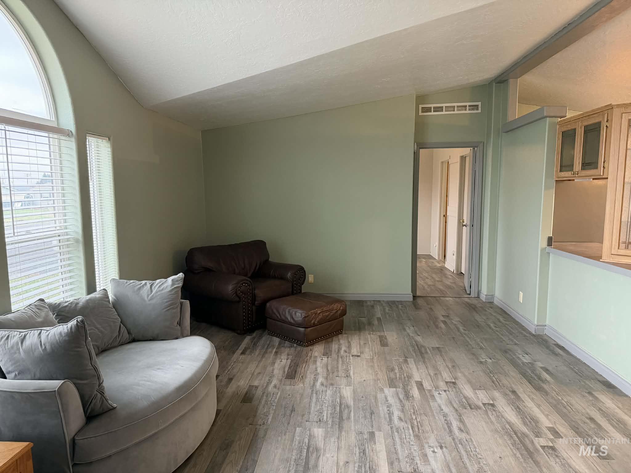 Living room featuring vaulted ceiling, wood finished floors, and a textured ceiling