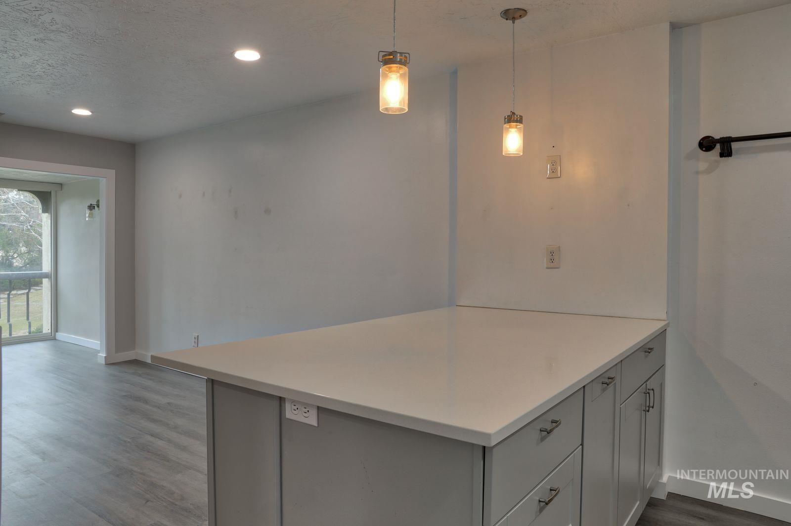 Kitchen featuring light countertops, dark wood-style flooring, decorative light fixtures, a peninsula, and a textured ceiling