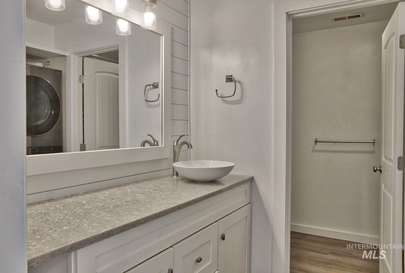 Bathroom with vanity, washer / clothes dryer, and wood finished floors